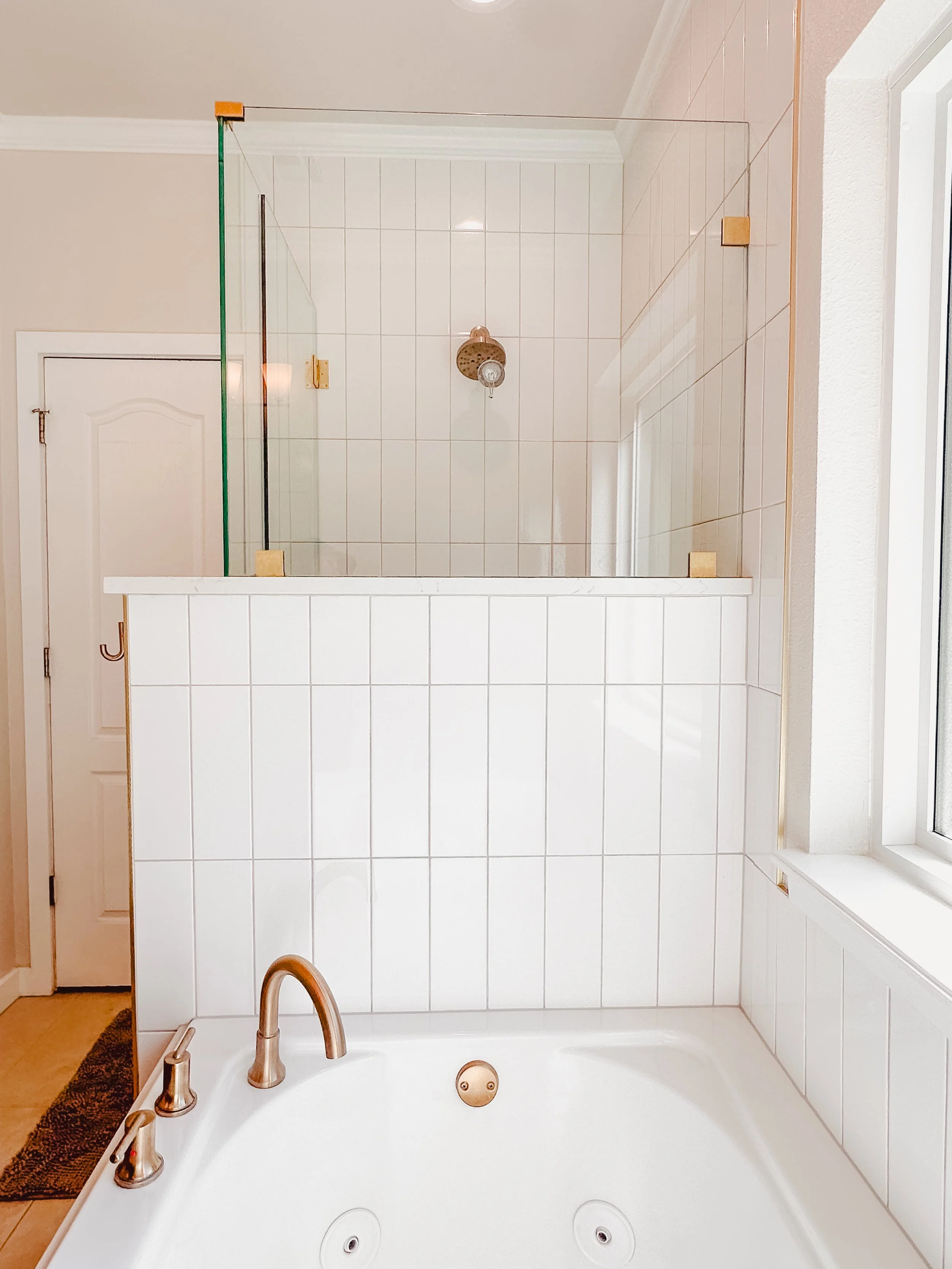 A bathroom with a corner shower with glass walls, and a bathtub with jets and a faucet, mirror, and a window.