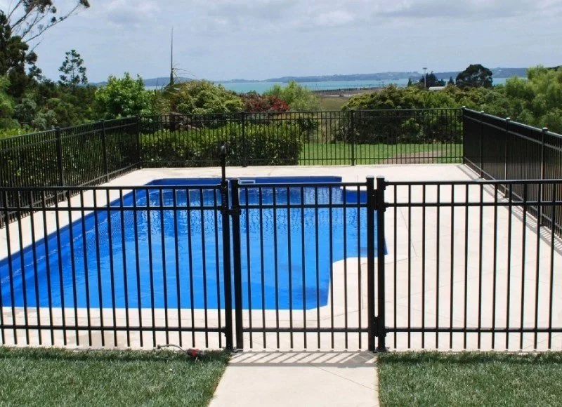 A flat top 3 rail black aluminum fence around a pool