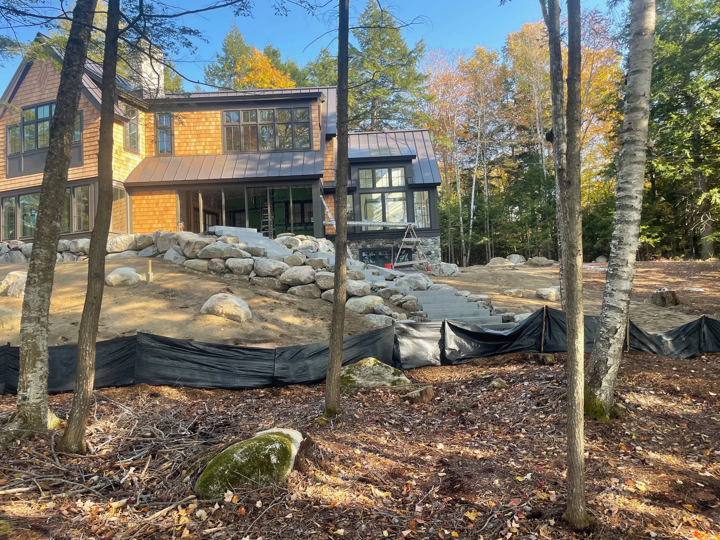 Undergoing construction, a house in a wooded area with trees, rocks, and steps leading up to it.