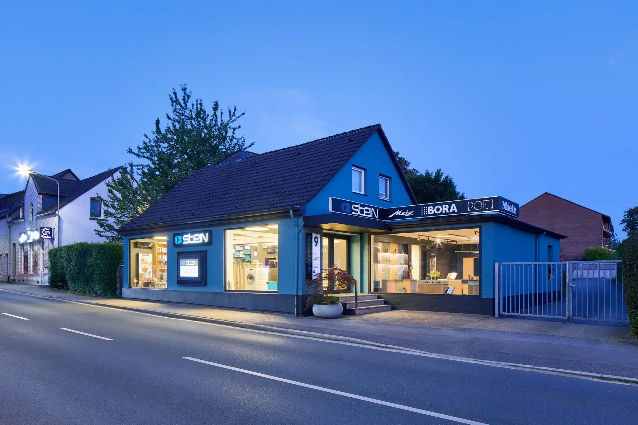 Firmensitz der Radion Alfred Stein GmbH in Ratingen, im Fenster sind Elektronikartikel zu sehen. Die Umgebung ist ruhig, es ist Abend oder Nacht.