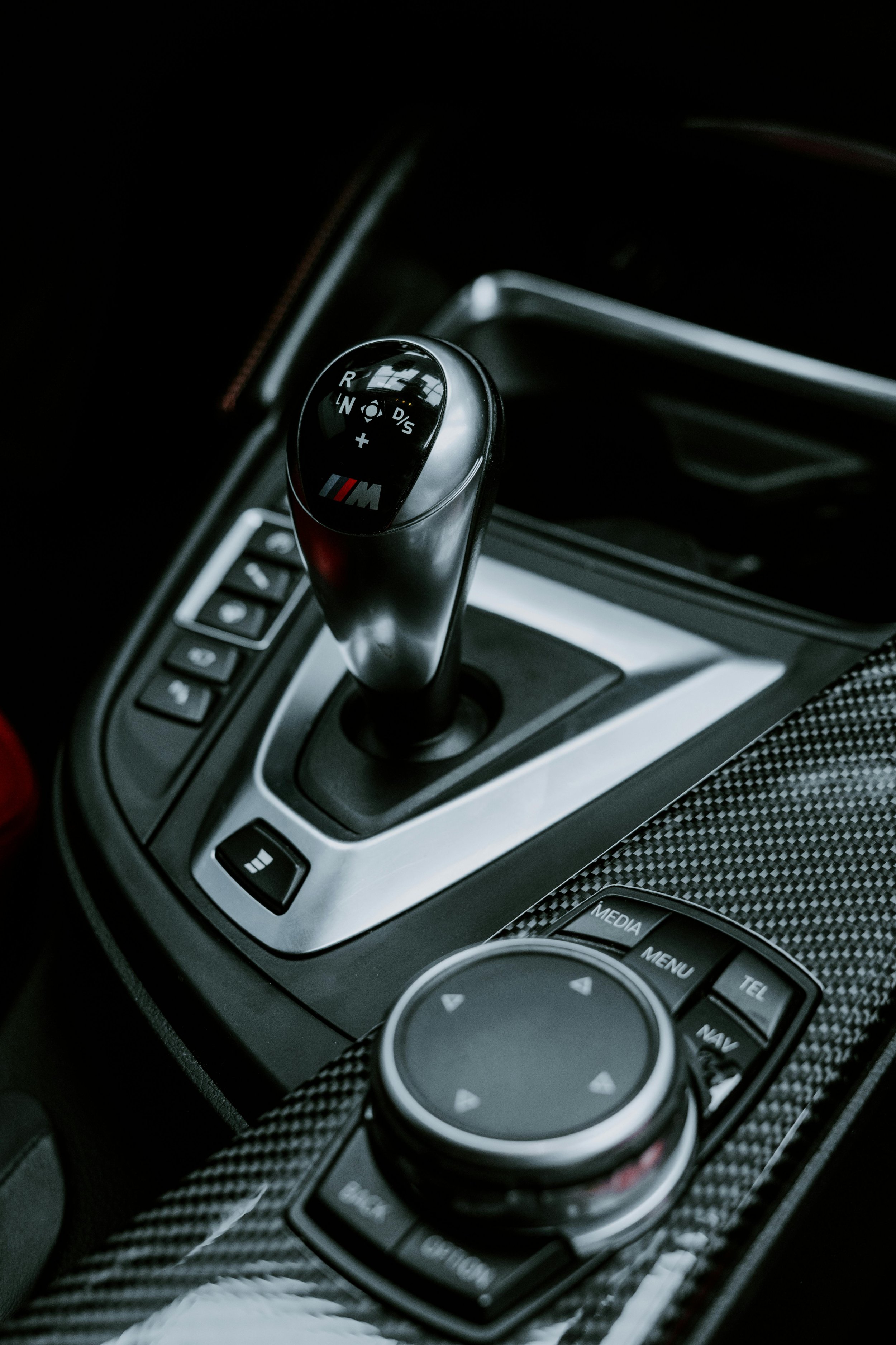Close-up of a BMW M Series sports car gear shifter with buttons and control panel.