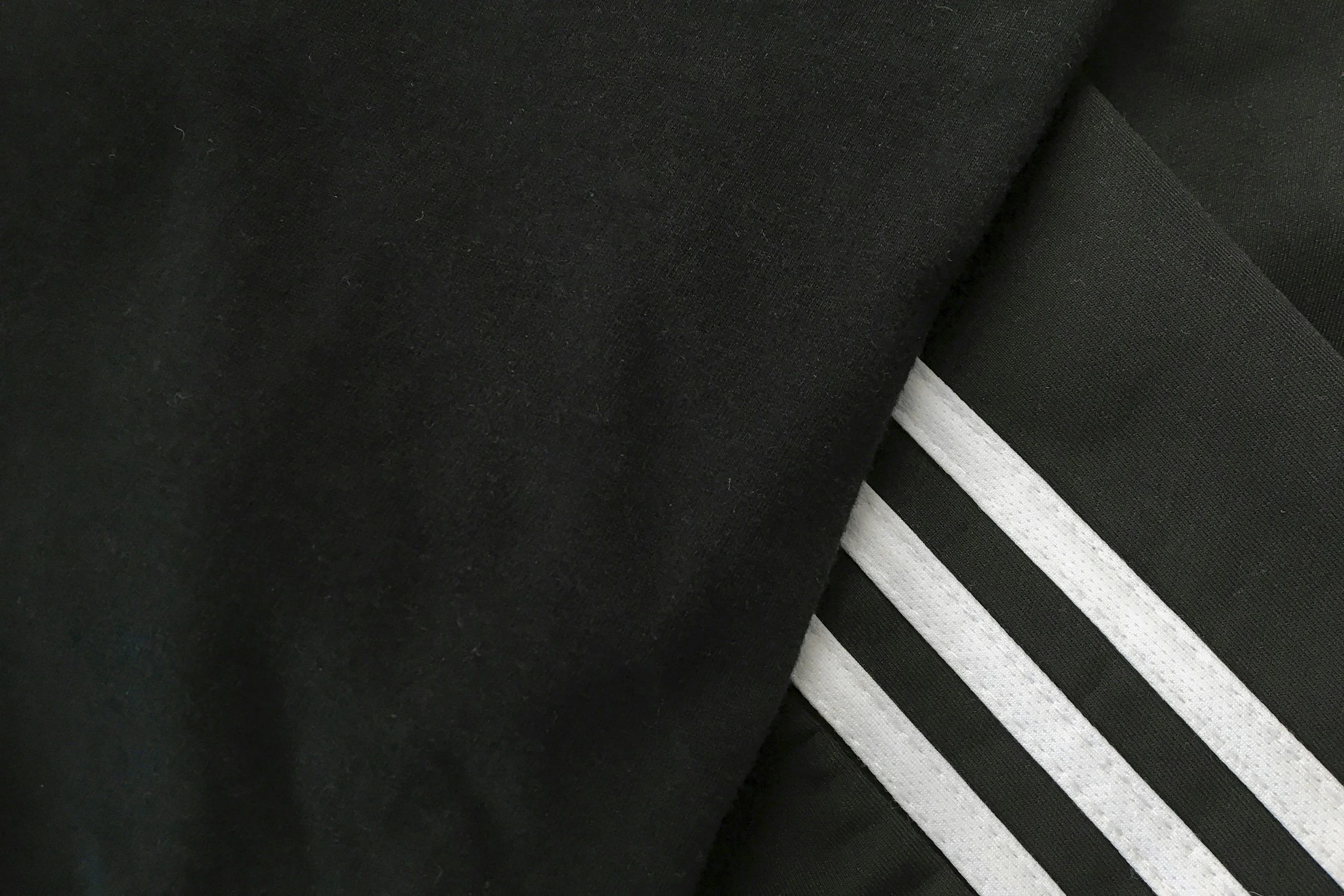 Close-up image of black fabric with white and black striped fabric layered underneath.