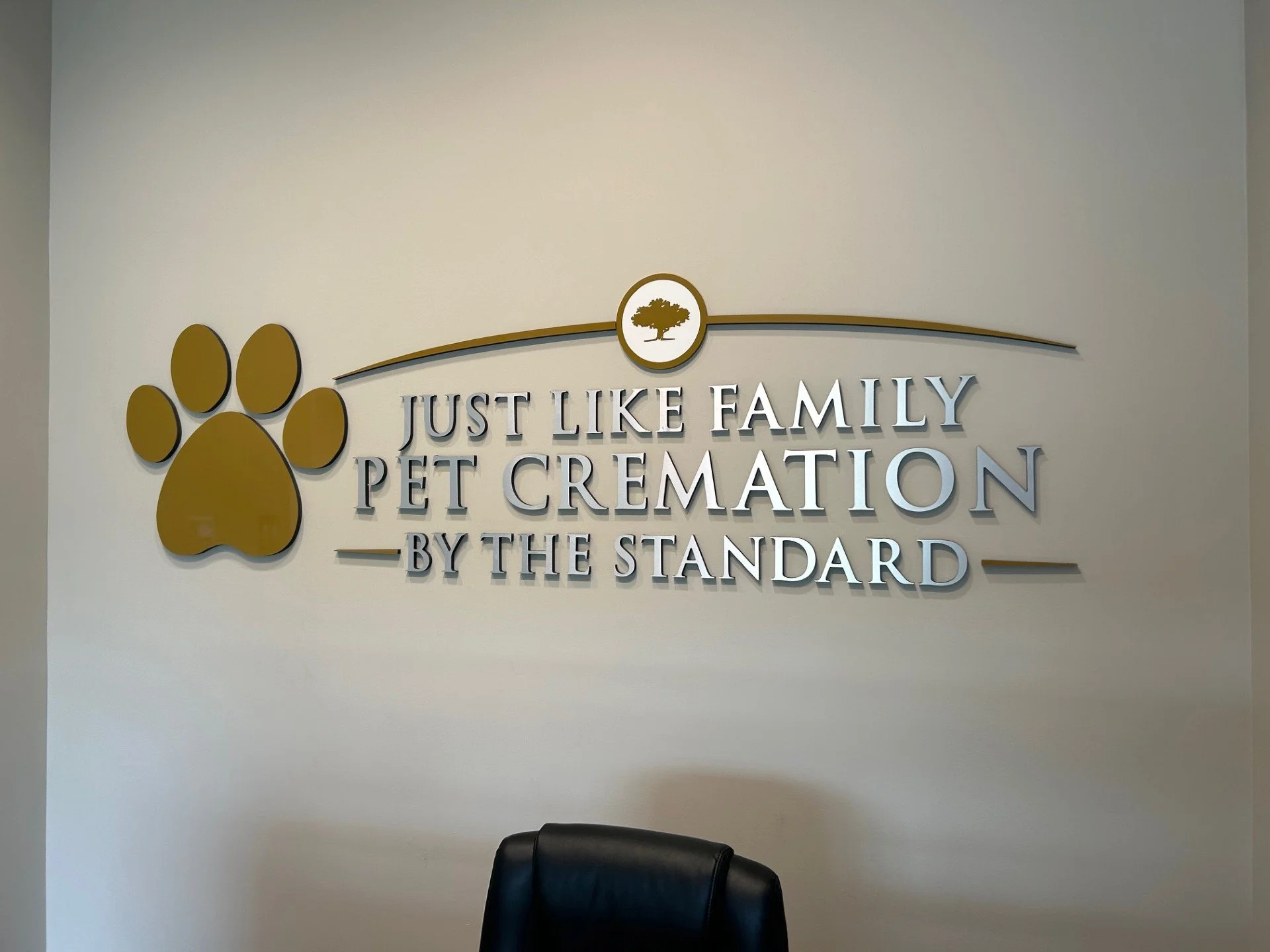 Interior wall with gold paw print logo and text that reads 'Just Like Family Pet Cremation by The Standard' and a small tree logo.