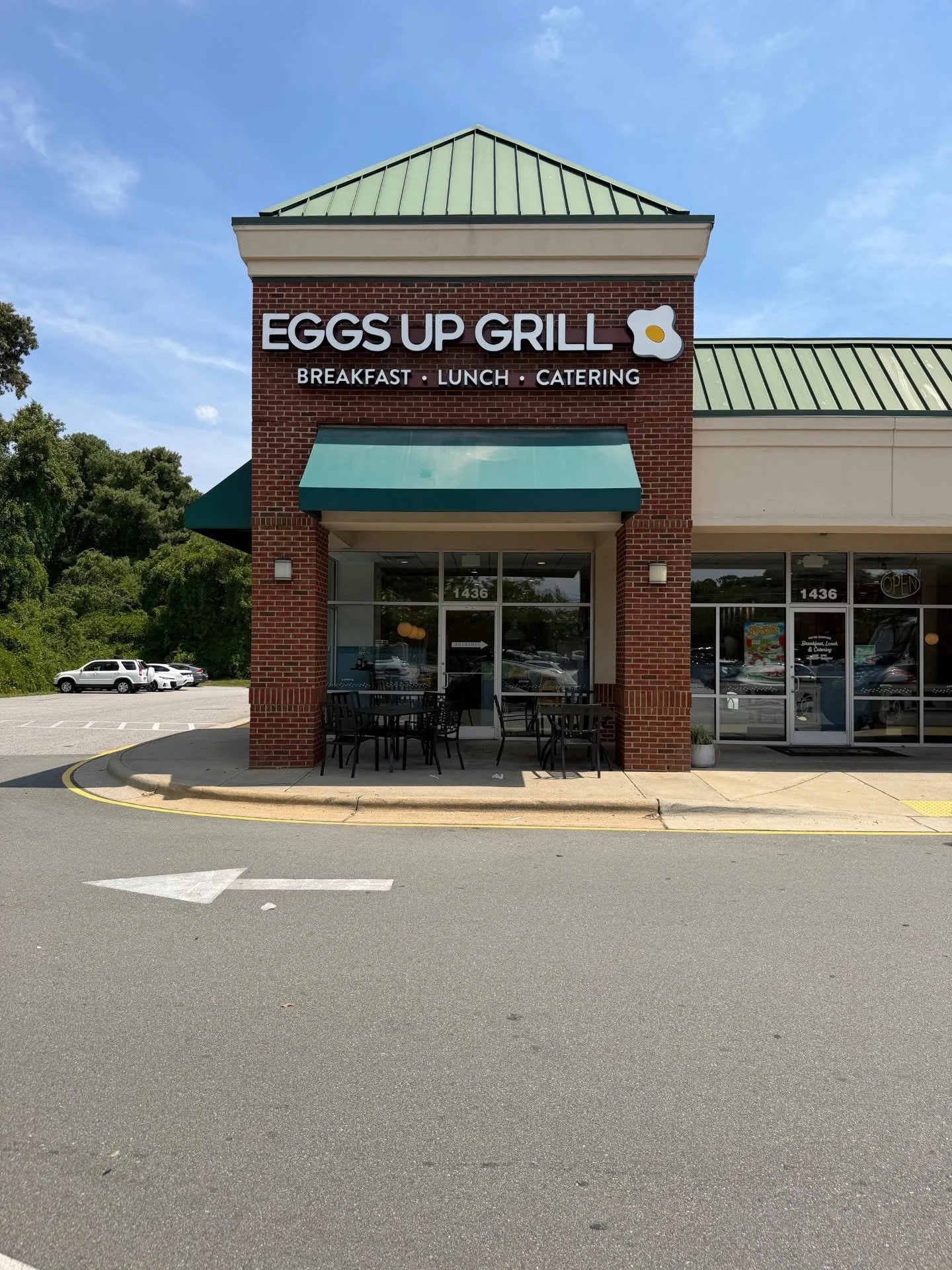 The exterior of a brick restaurant called Eggs Up Grill, with a sign featuring a fried egg graphic. Wall-mounted, lighted storefront sign with graphic logo in Raleigh, North Carolina