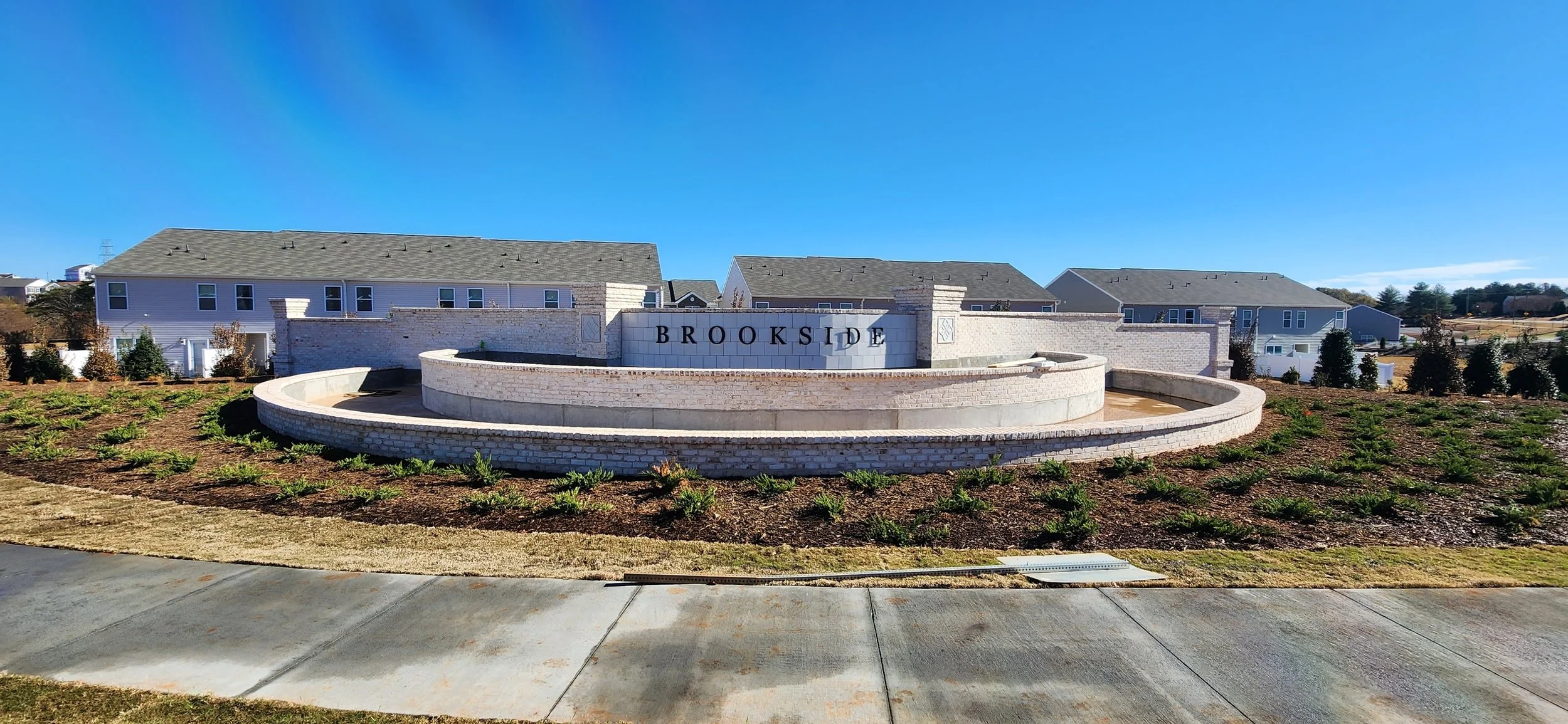 Nelsonville Apartments entrance sign with landscaped area and residential buildings in the background under a clear blue sky.