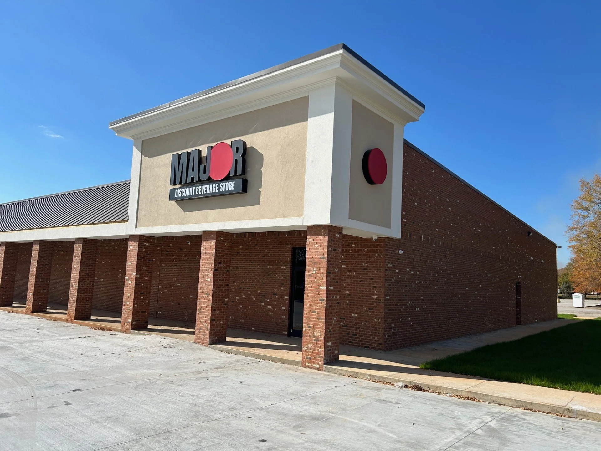 The exterior of a MajR discount beverage store building with brick walls and a sign on the facade, under a clear blue sky.