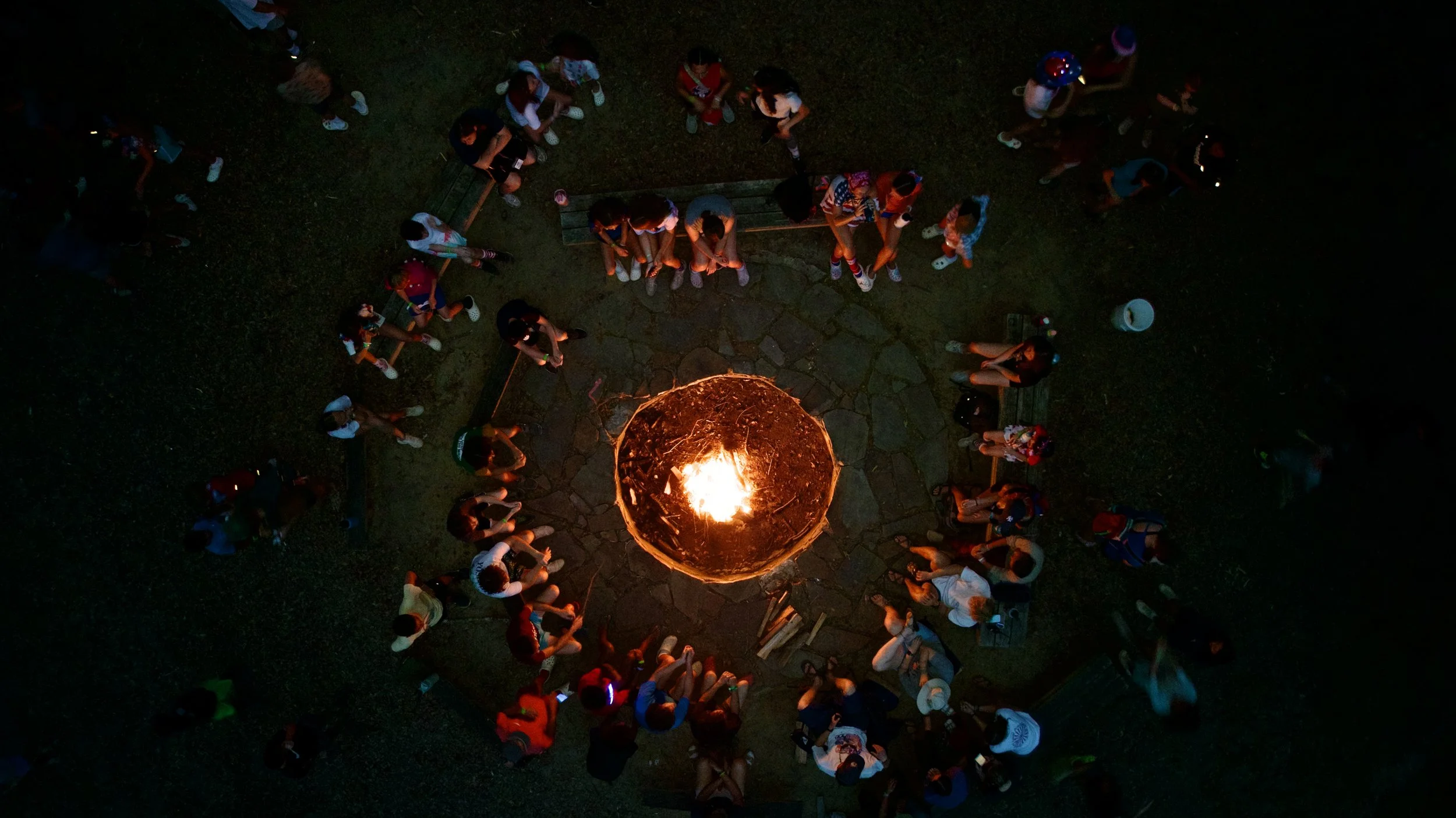 People gathered around a campfire viewed from above at night at Riverstone at Canaan.