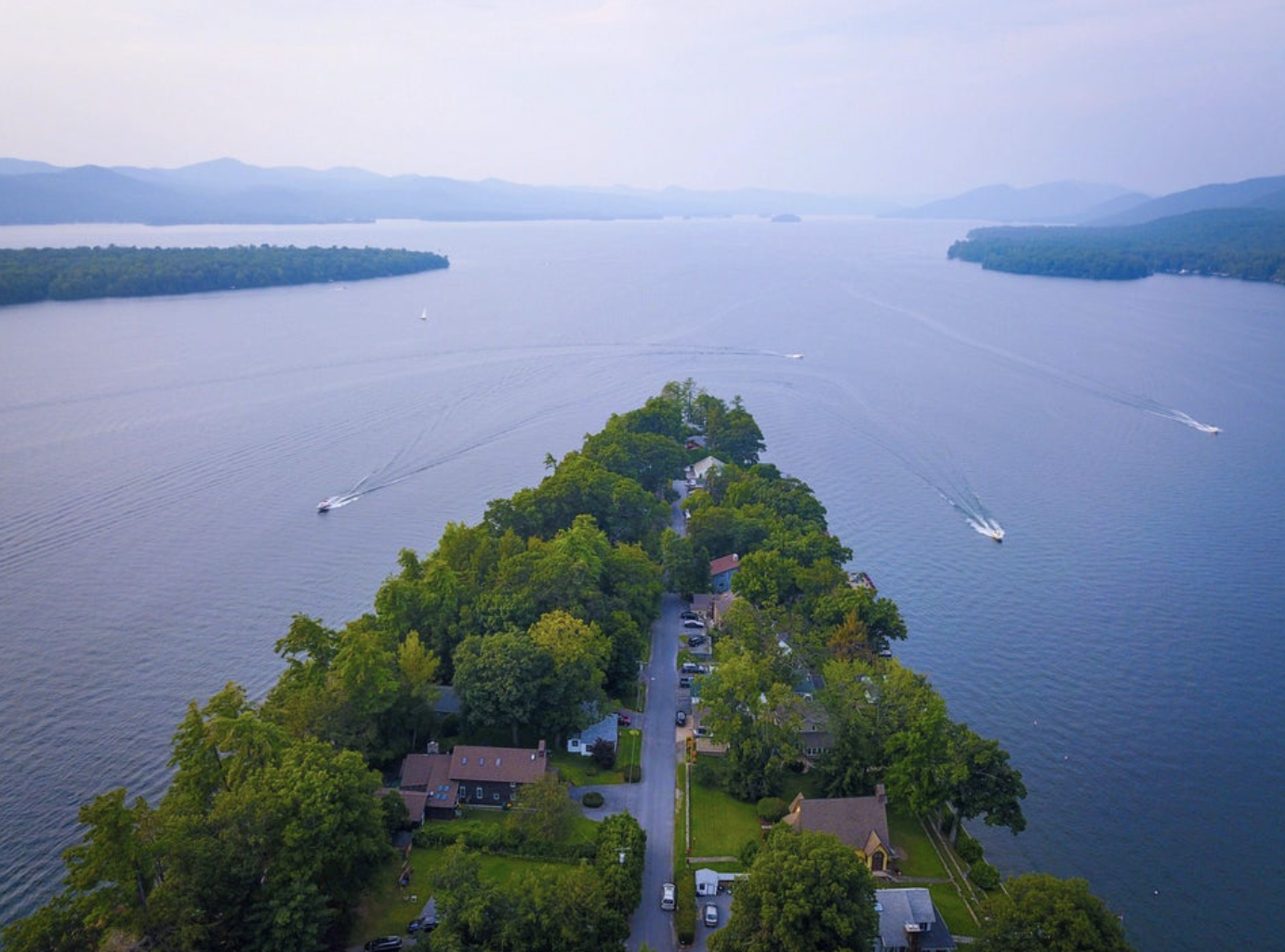 Kitchen with white cabinets, gray countertops, open wooden shelves with decorative bowls, glasses, books, and plates, stainless steel appliances, and wooden utensils.