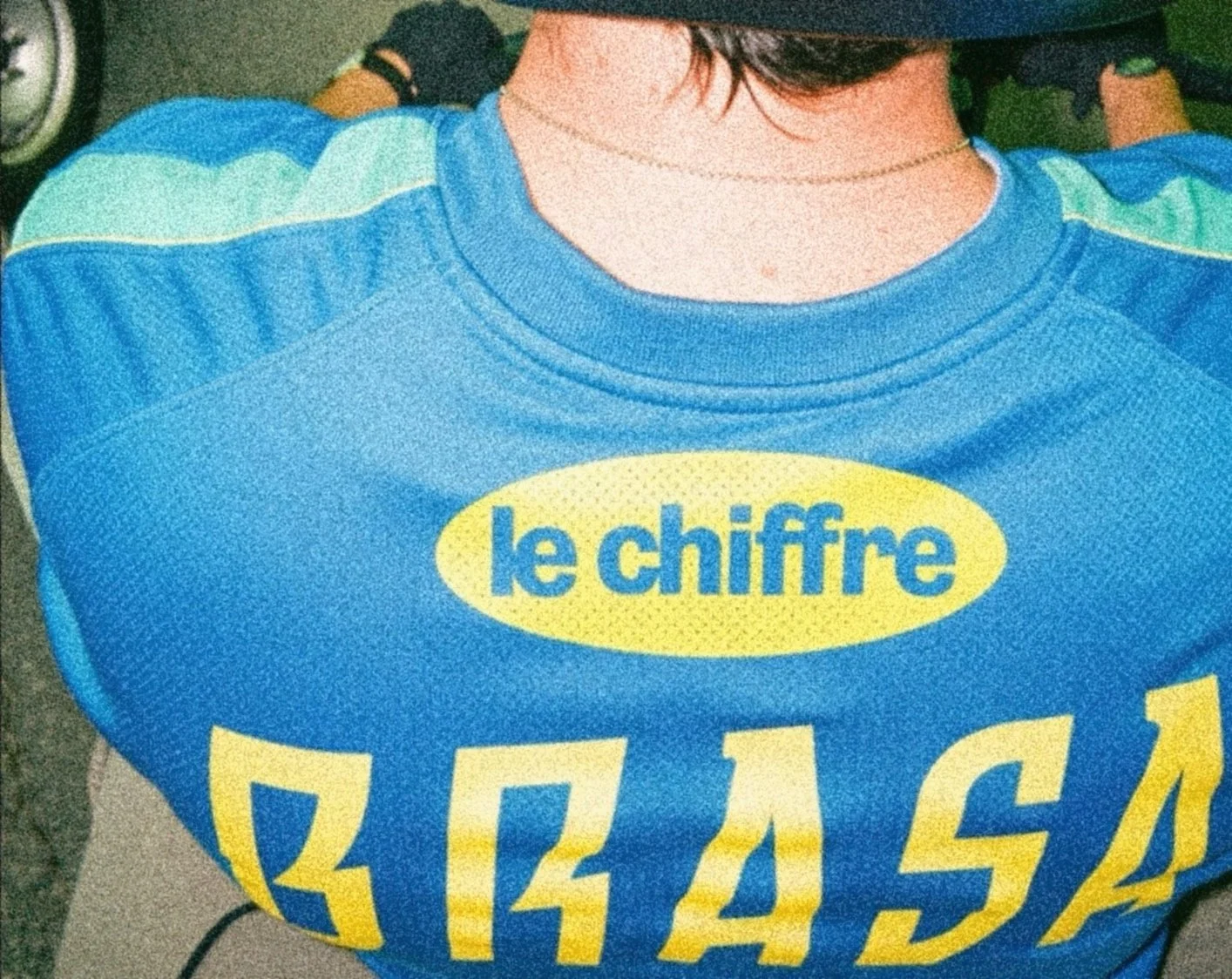 Personne portant un sweat avec l'inscription "le chiffre" en français, en couleur jaune et bleu.