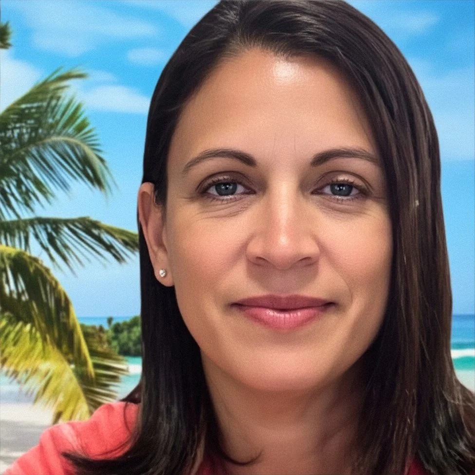 Close-up of a woman with dark brown hair and blue eyes smiling against a beach background with palm trees, blue sky, and ocean.