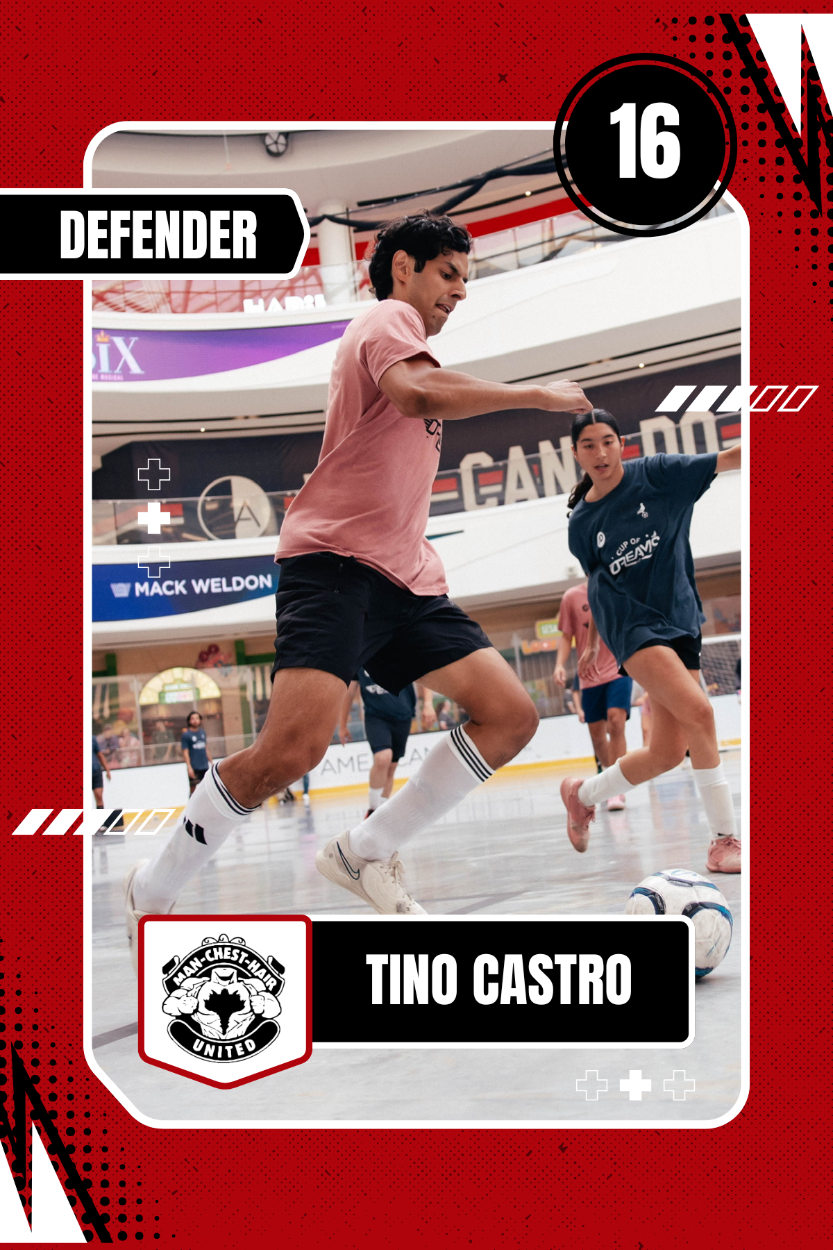 A Dragon-Chest-Har United soccer player in a pink shirt and black shorts playing indoor soccer, kicking a ball, with a female player in a blue shirt in the background, in a large indoor arena.