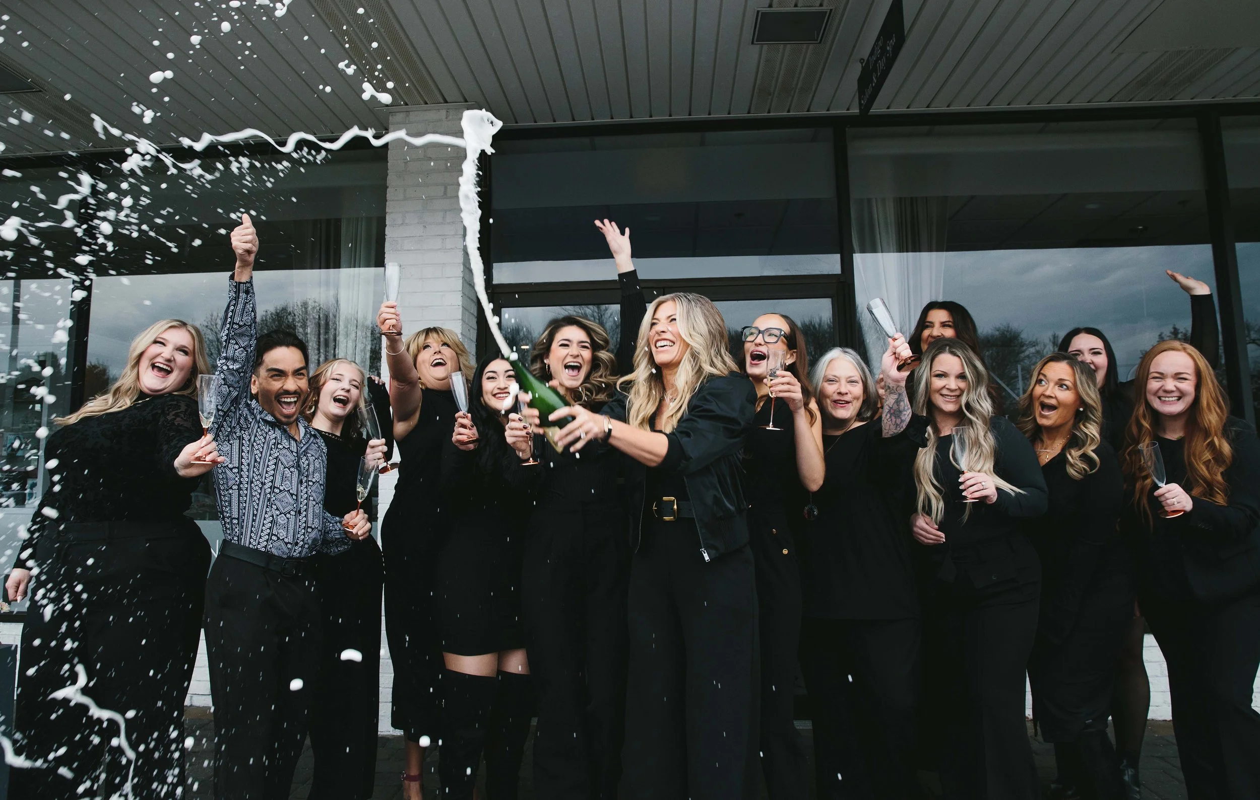 People celebrating with champagne and confetti on outdoors patio.