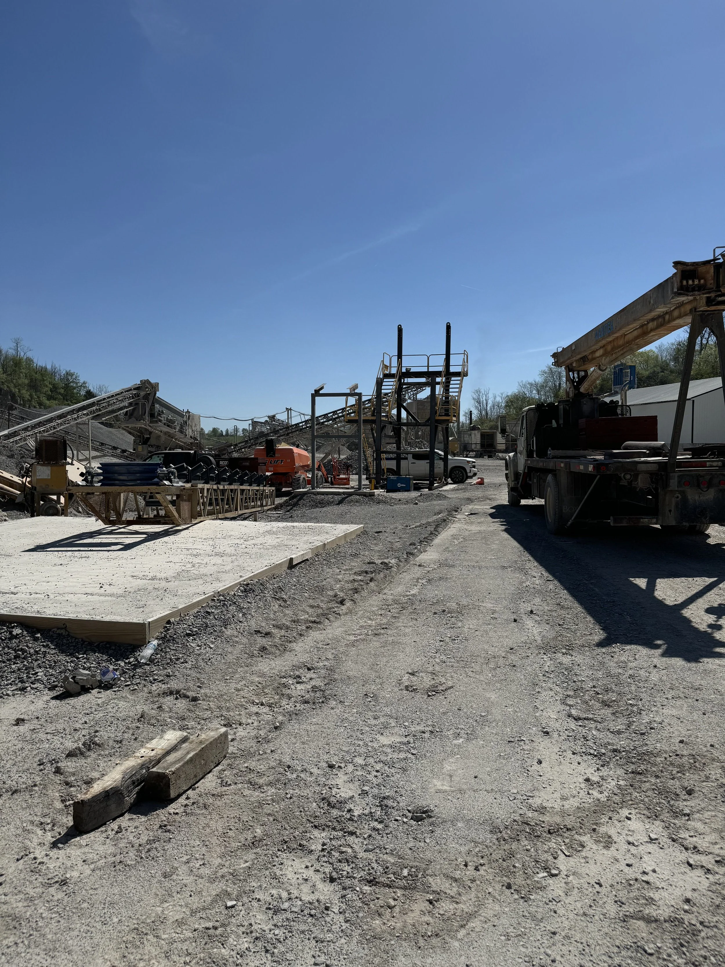 Construction site with equipment, gravel ground, and blue sky.