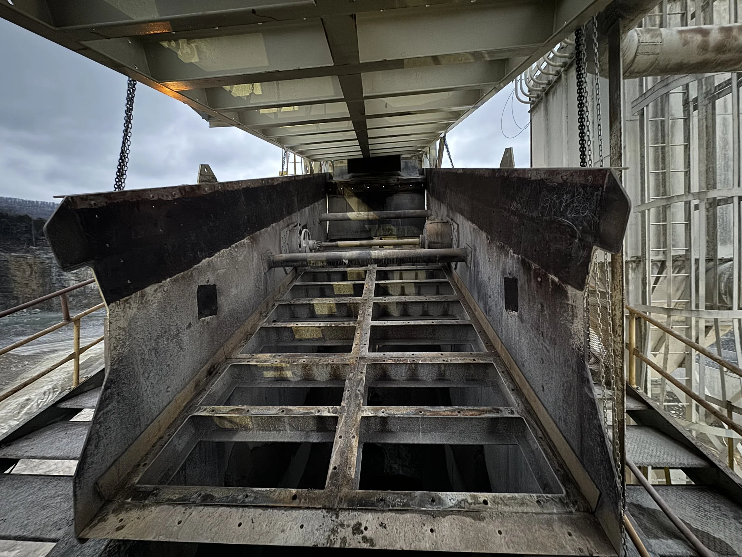 Industrial construction site with metal stairs, scaffolding, and equipment under a cloudy sky.