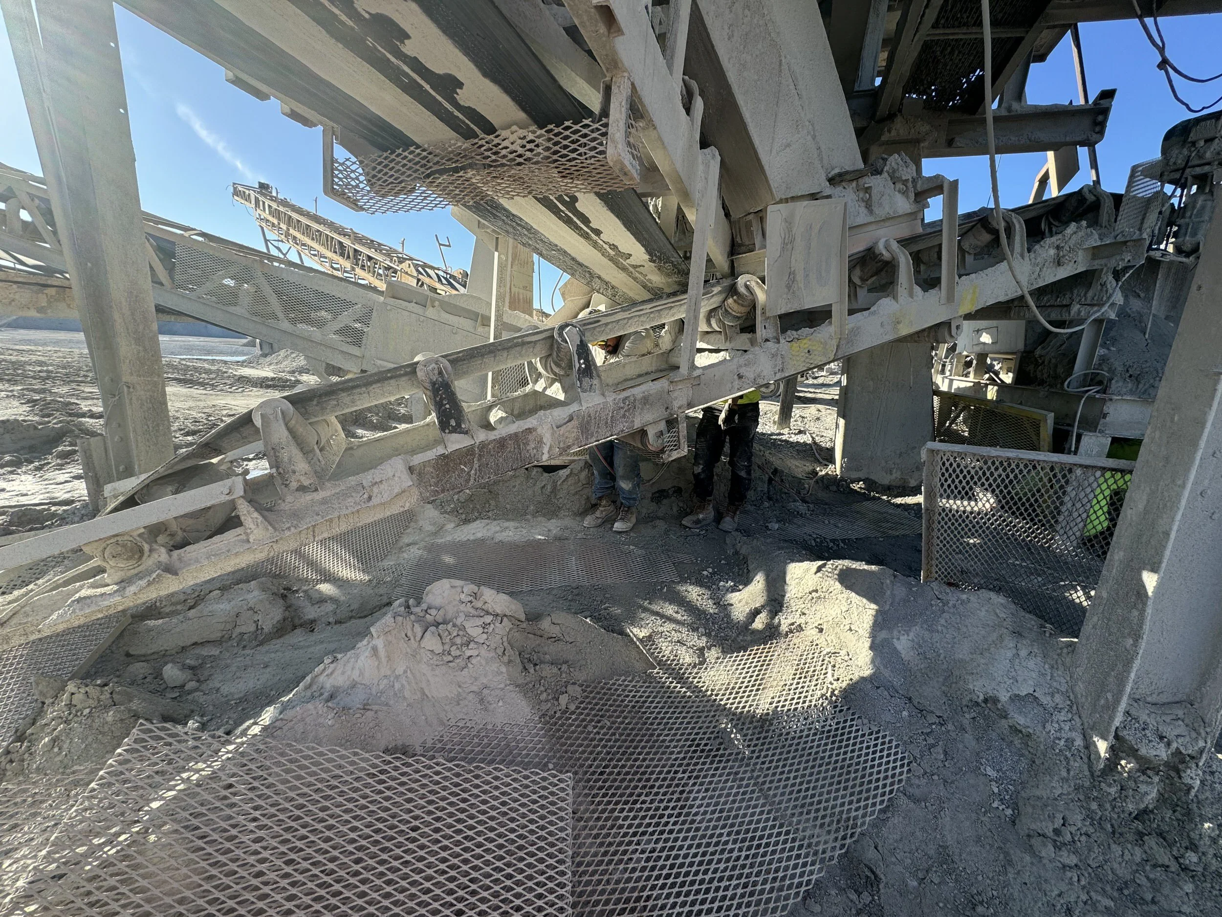 Construction site with large machinery moving dirt, surrounded by metal scaffolding and workers.