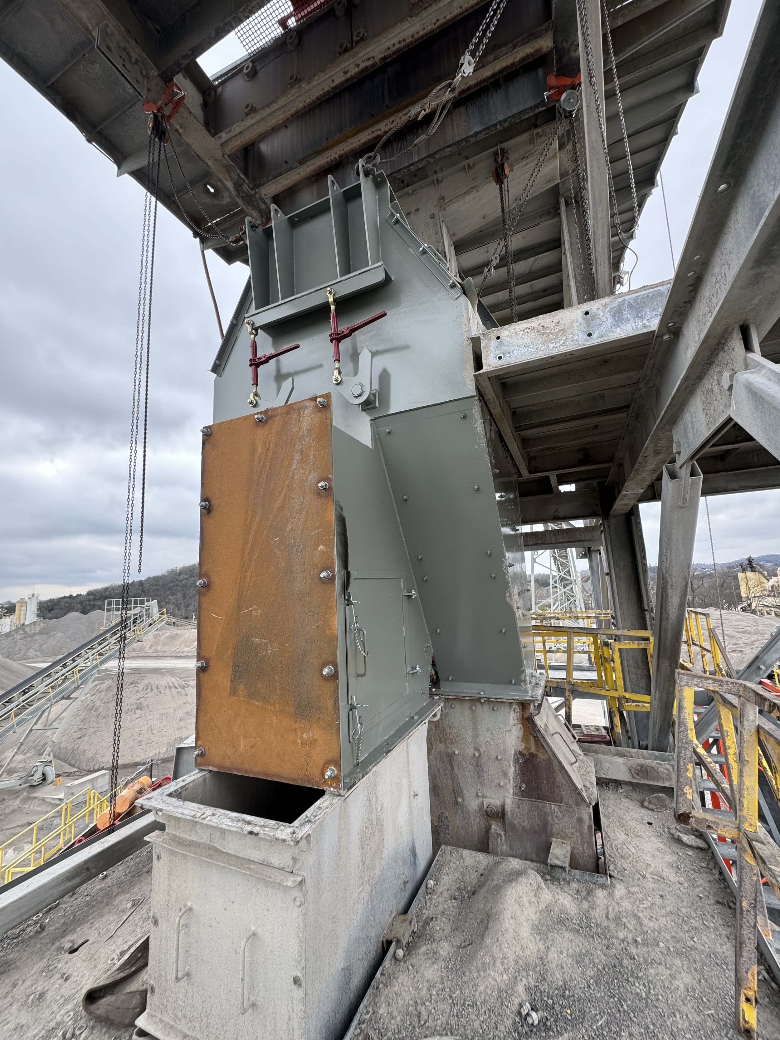 Close-up of industrial construction equipment with metal framework, chains, and structural components at a construction site.