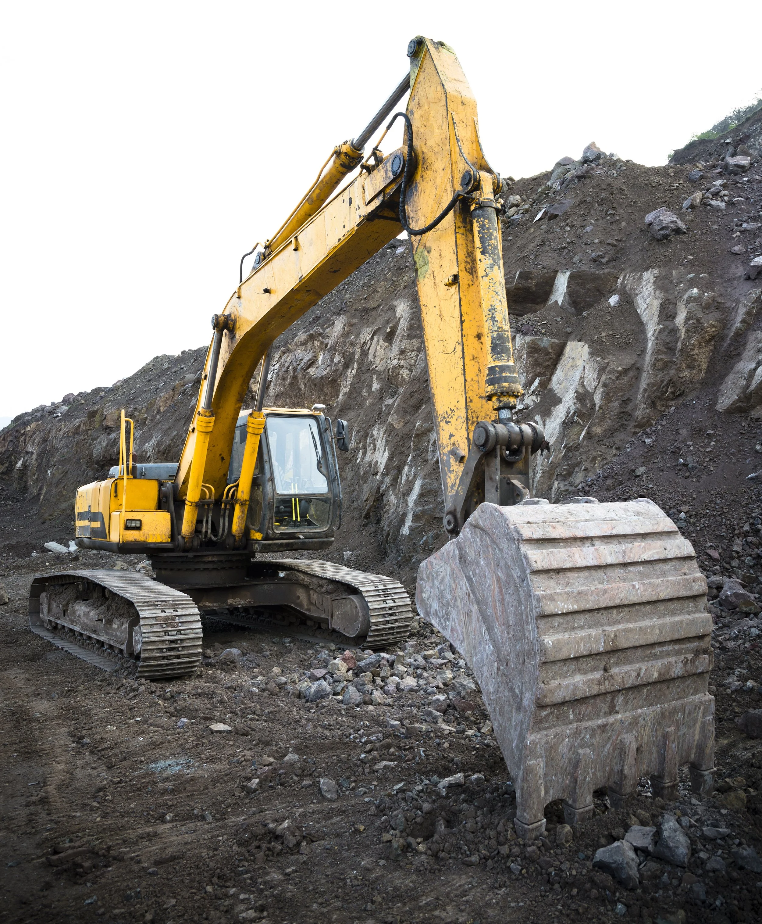 A yellow excavator working on a rocky hillside at a construction site.