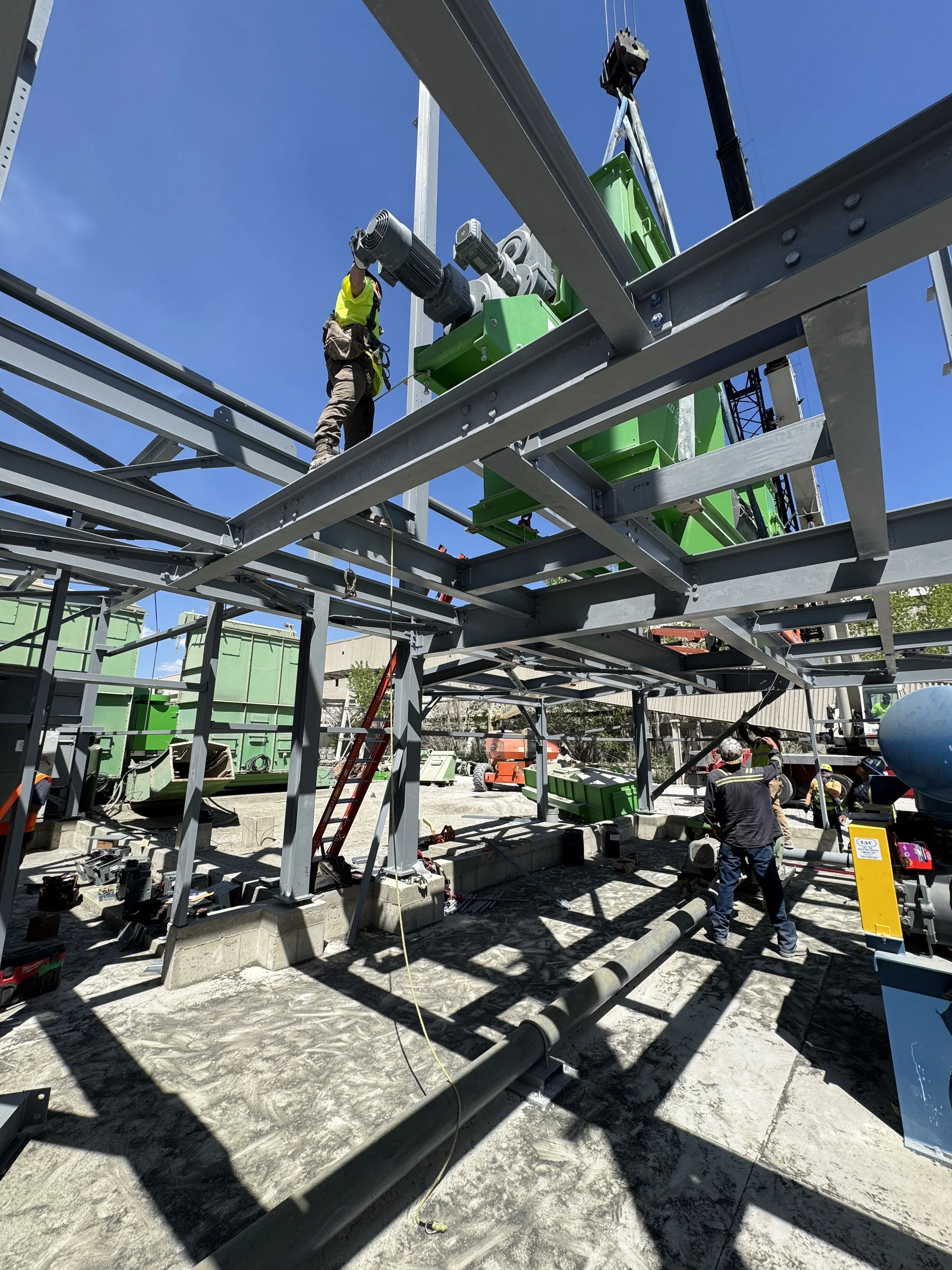 Construction workers building a steel framework at a construction site on a sunny day.