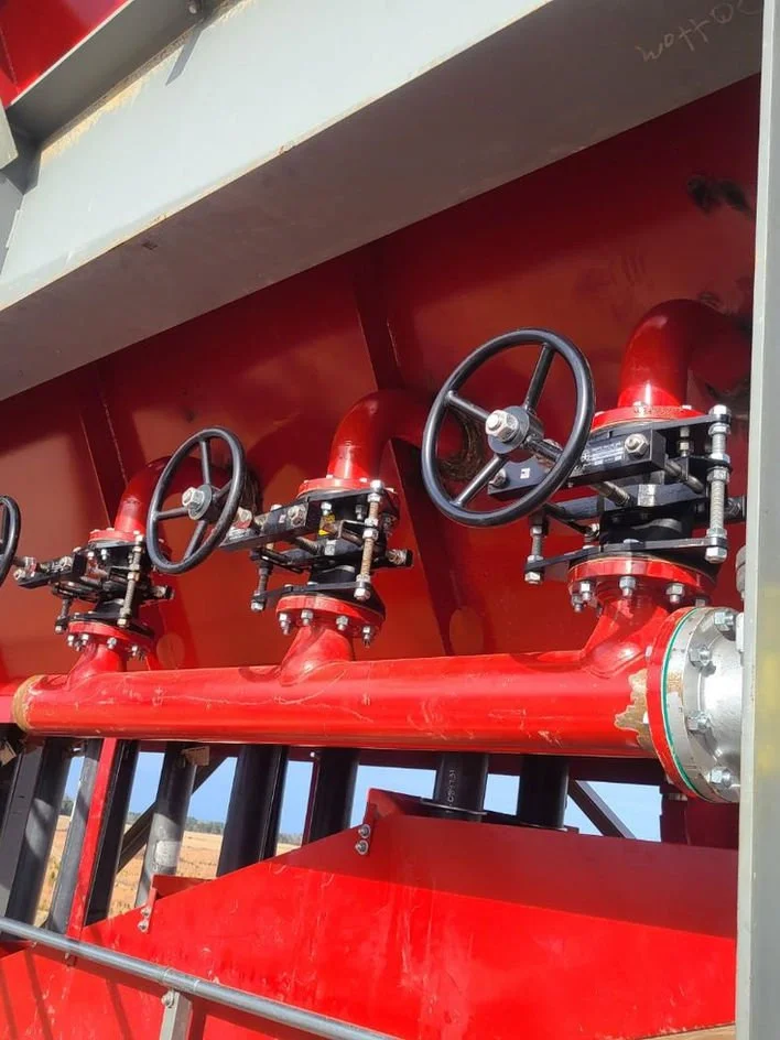 Close-up of fire control system with red valves, black handles, and metal piping.