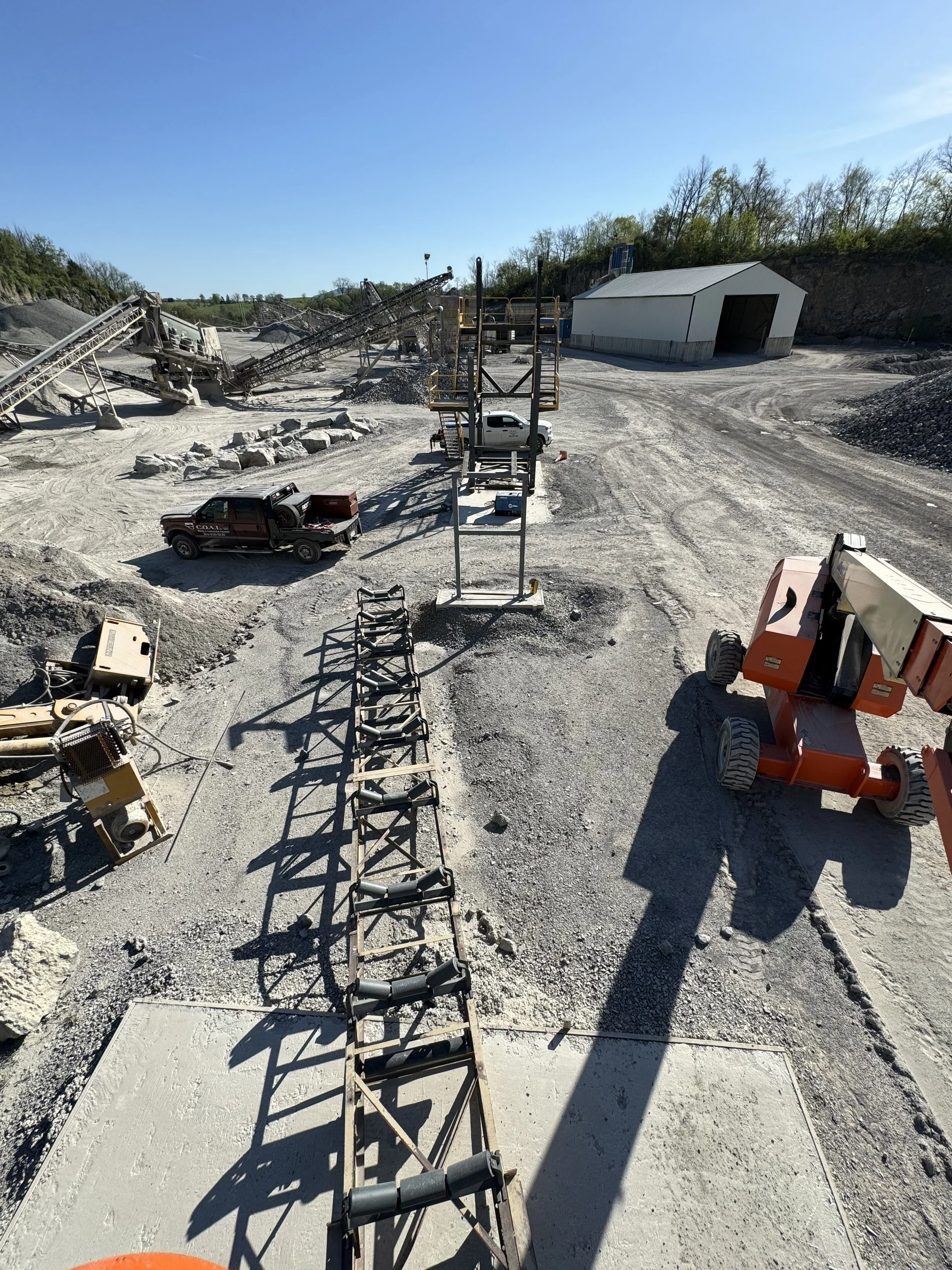 Construction site with machinery, trucks, and a building while setting concrete for a sidewalk or pathway.
