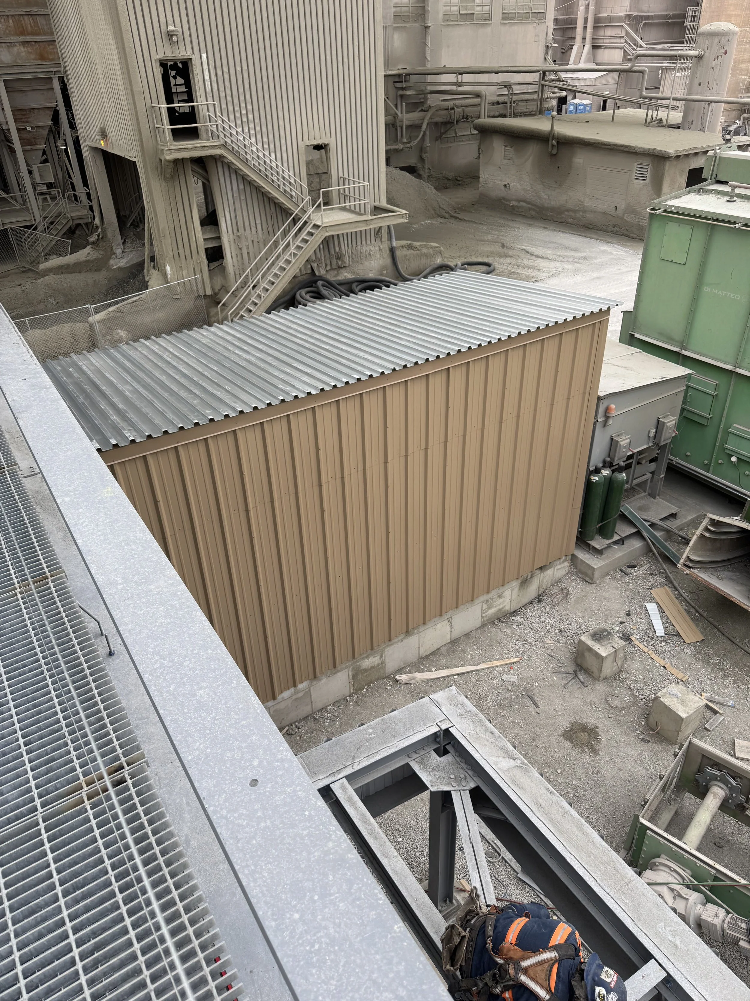 Construction site with scaffolding, metal stairs, and a large beige storage container.