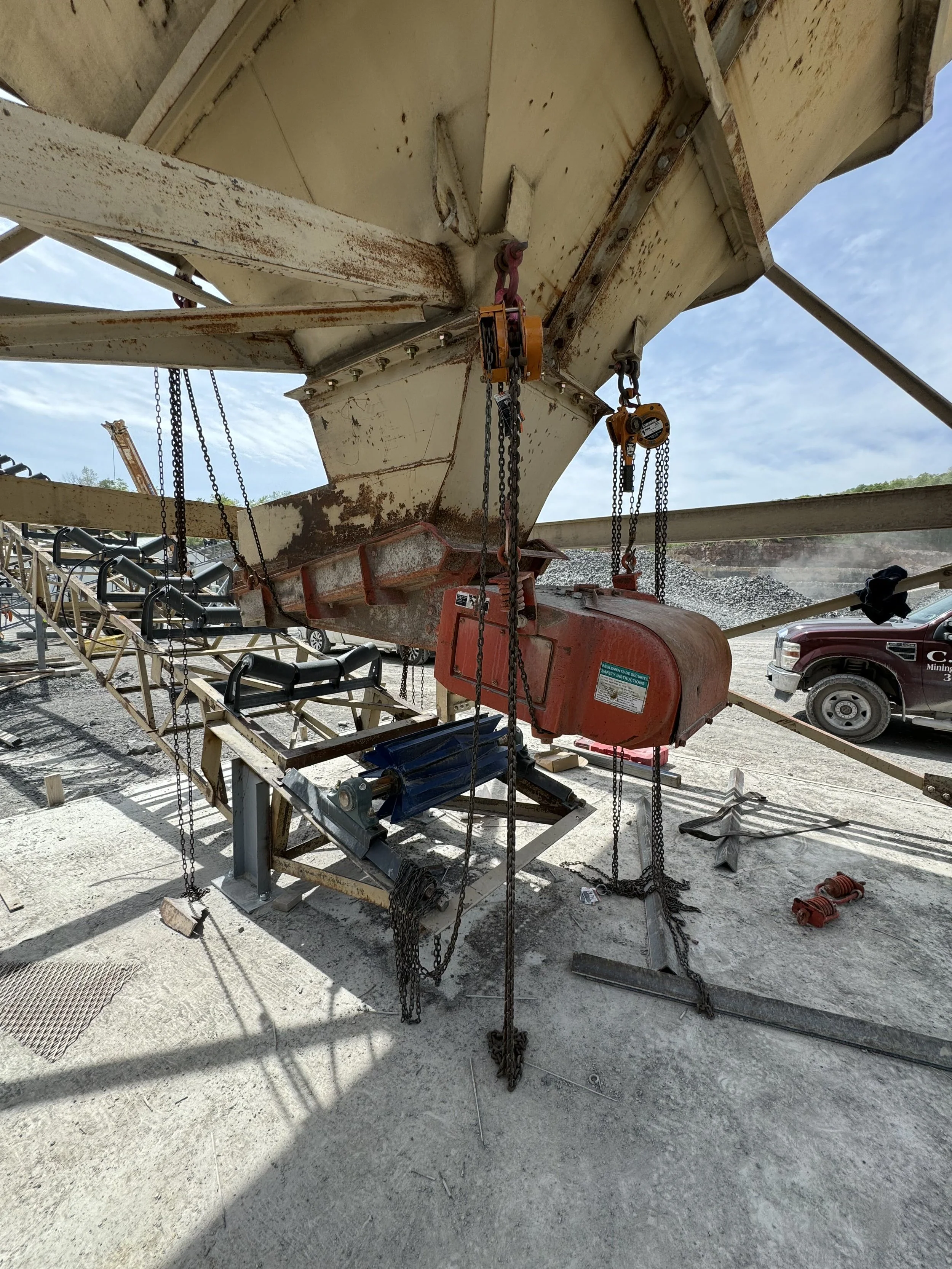 Underwater construction site with scaffolding and equipment, part of a large rusty ship or submarine, with a truck visible in the background.