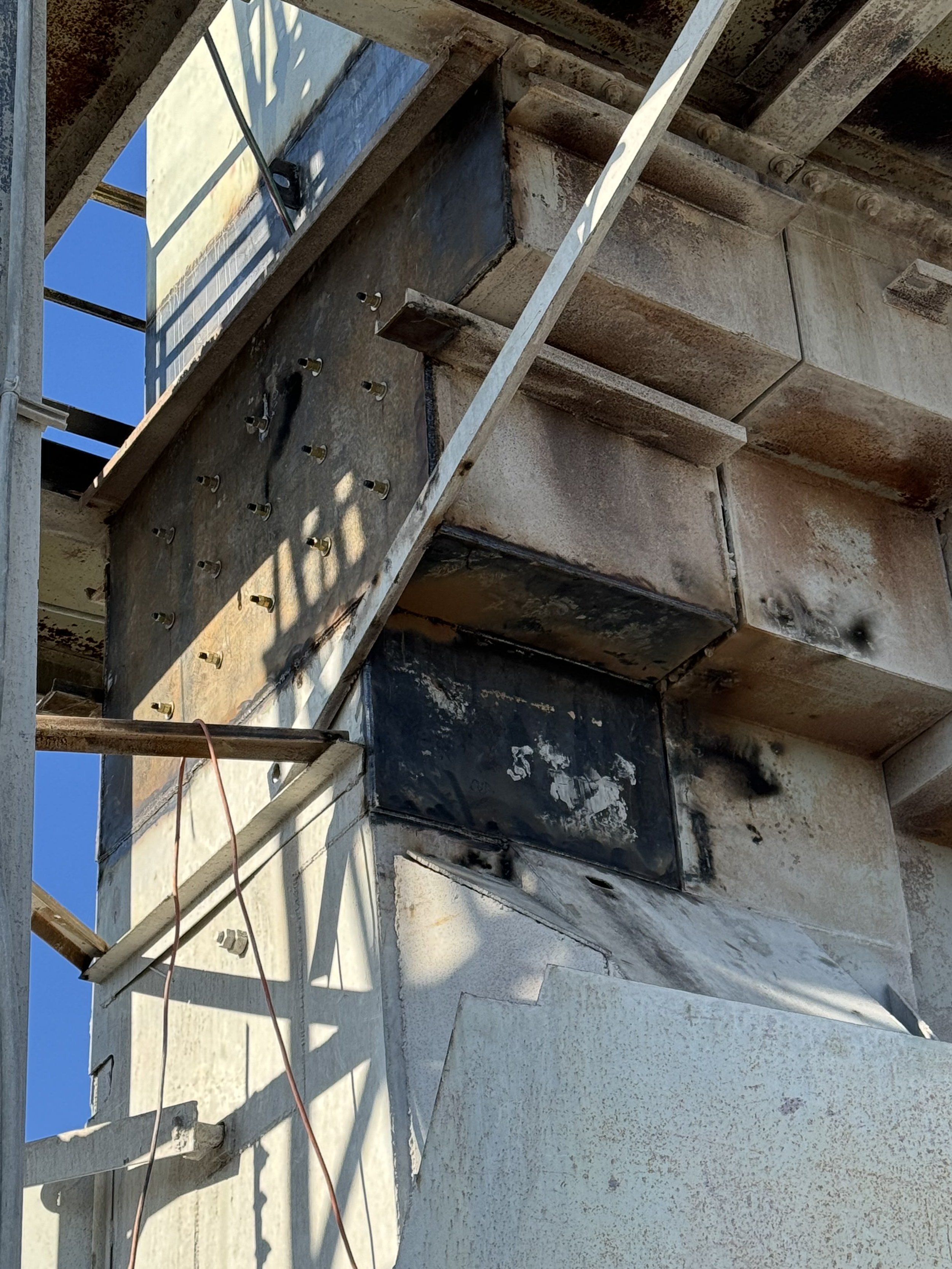 View of a construction site showing steel reinforcements, concrete, and formwork for building a structural element, under clear blue sky.
