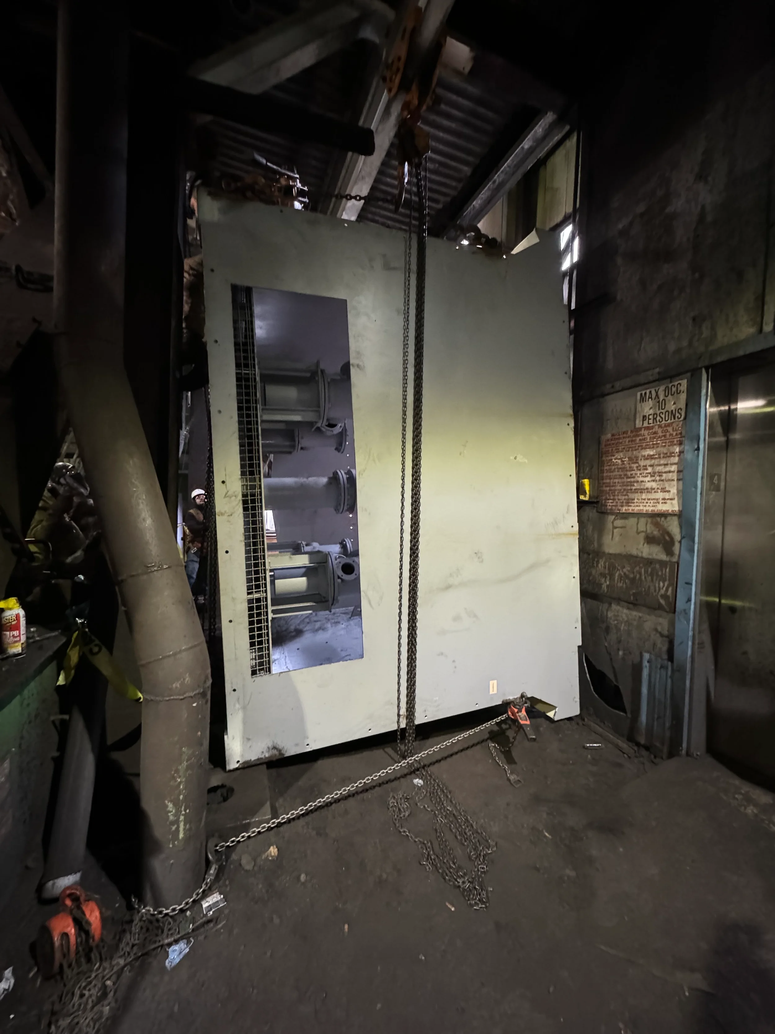 Industrial electrical panel or machinery in a warehouse, surrounded by chains and safety equipment.