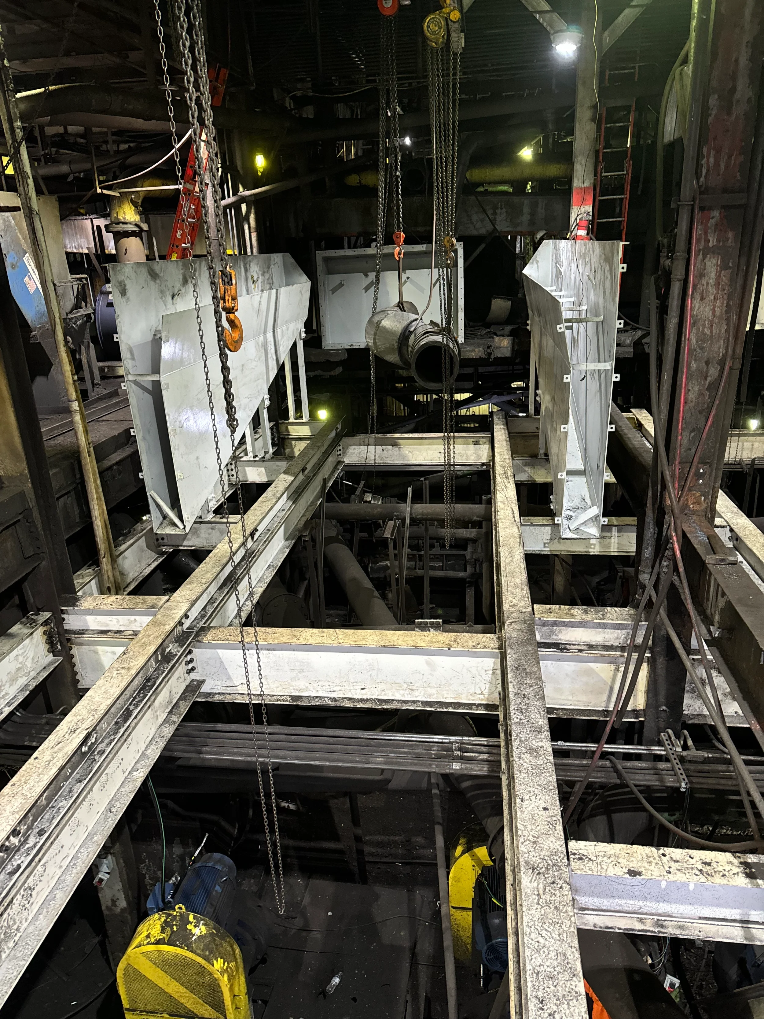 Construction site with metal framing, chains, ladders, and industrial equipment in a dark workspace.