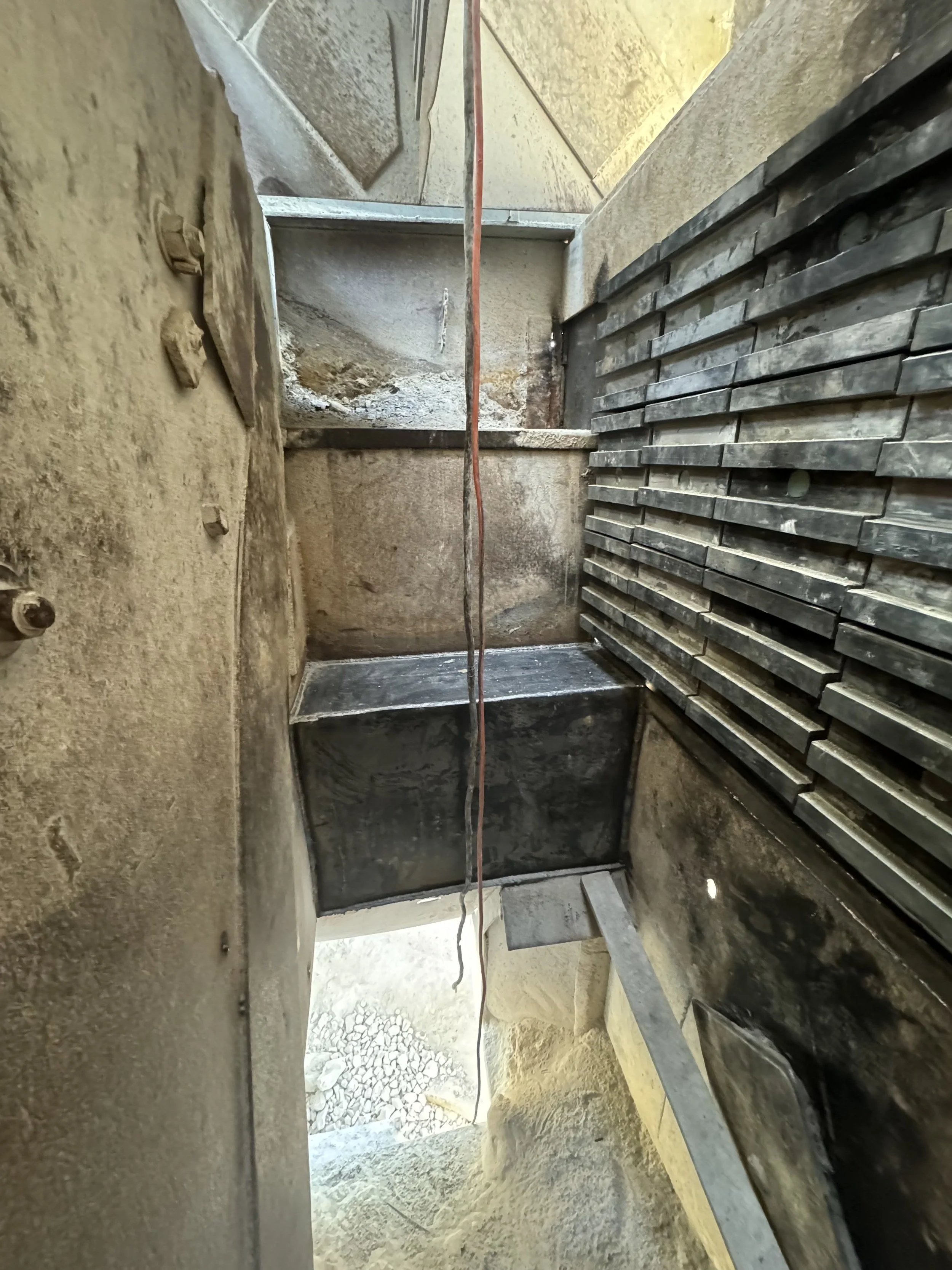 Construction site with metal framework, stacked metal bars, and rough concrete walls, indicating ongoing building or renovation work.