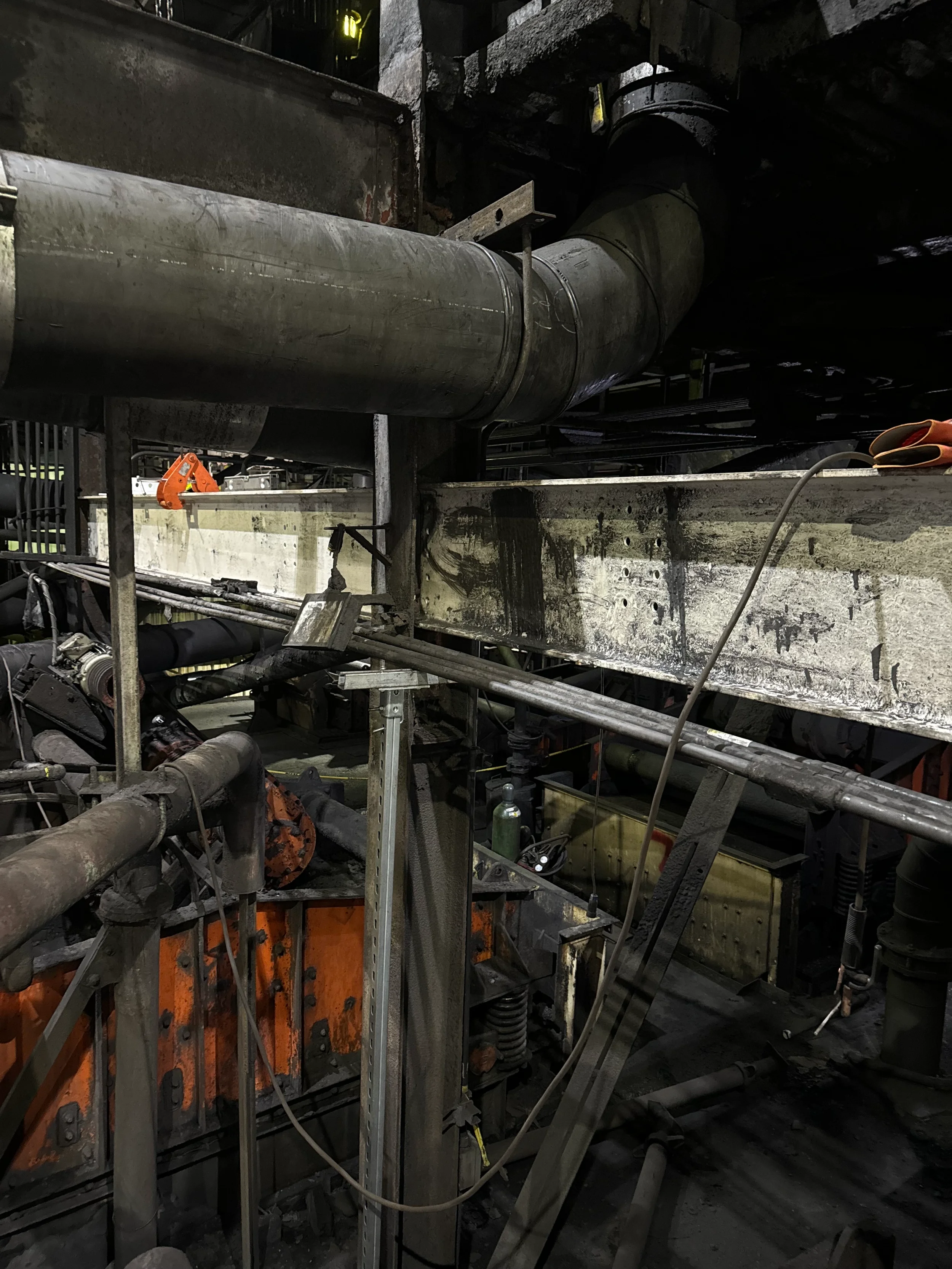 Close-up view of large industrial pipes and machinery in a dark factory or construction site.