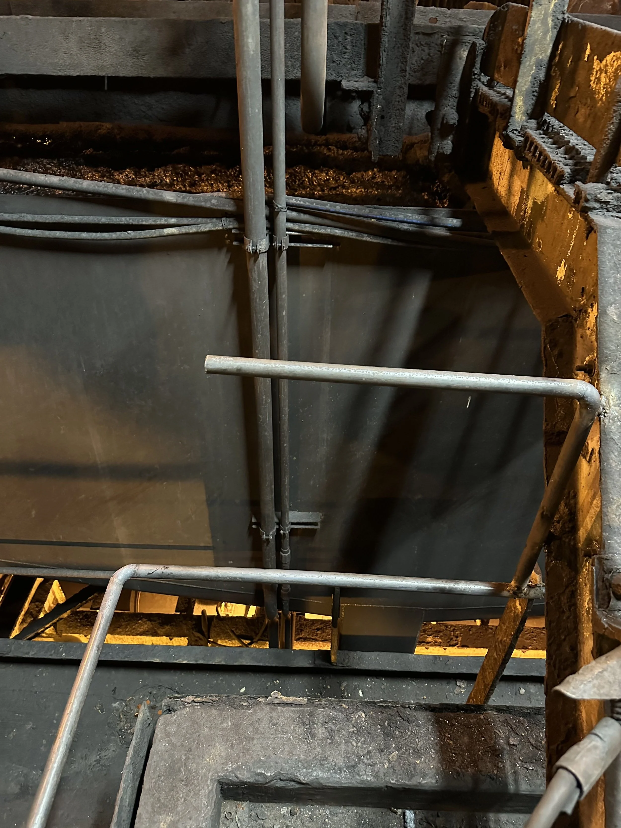 Construction site with metal scaffolding, pipes, brick wall, and concrete structures.