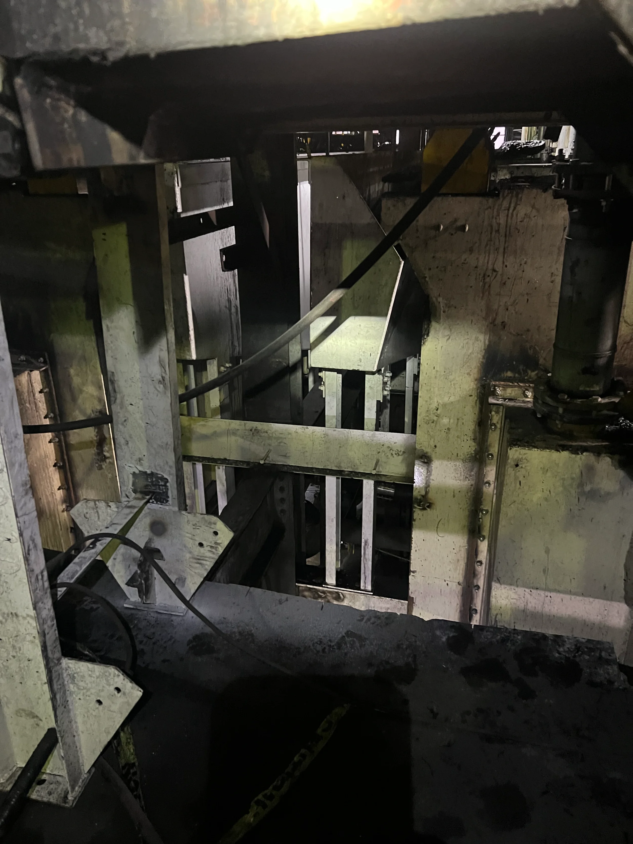 The inside of a large industrial machine or robotic equipment with metal and mechanical parts, wires, and hydraulic components, showing a complex assembly of machinery.