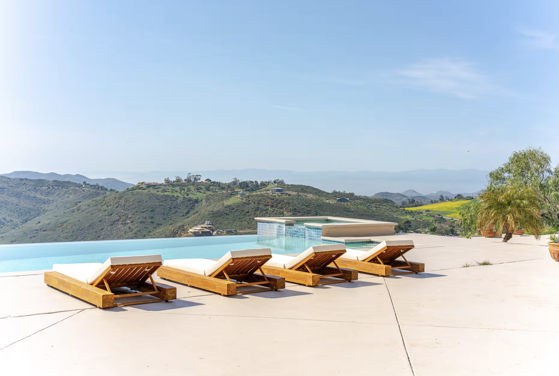 Poolside with wooden lounge chairs overlooking a scenic mountain view.