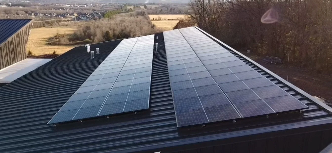 Solar panels installed on the roof of a building with a rural landscape in the background.