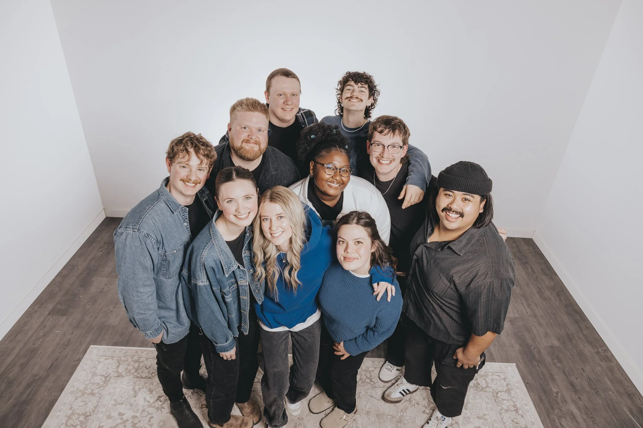 Group of worship leaders smiling and standing close together in a room with white walls and a patterned rug.