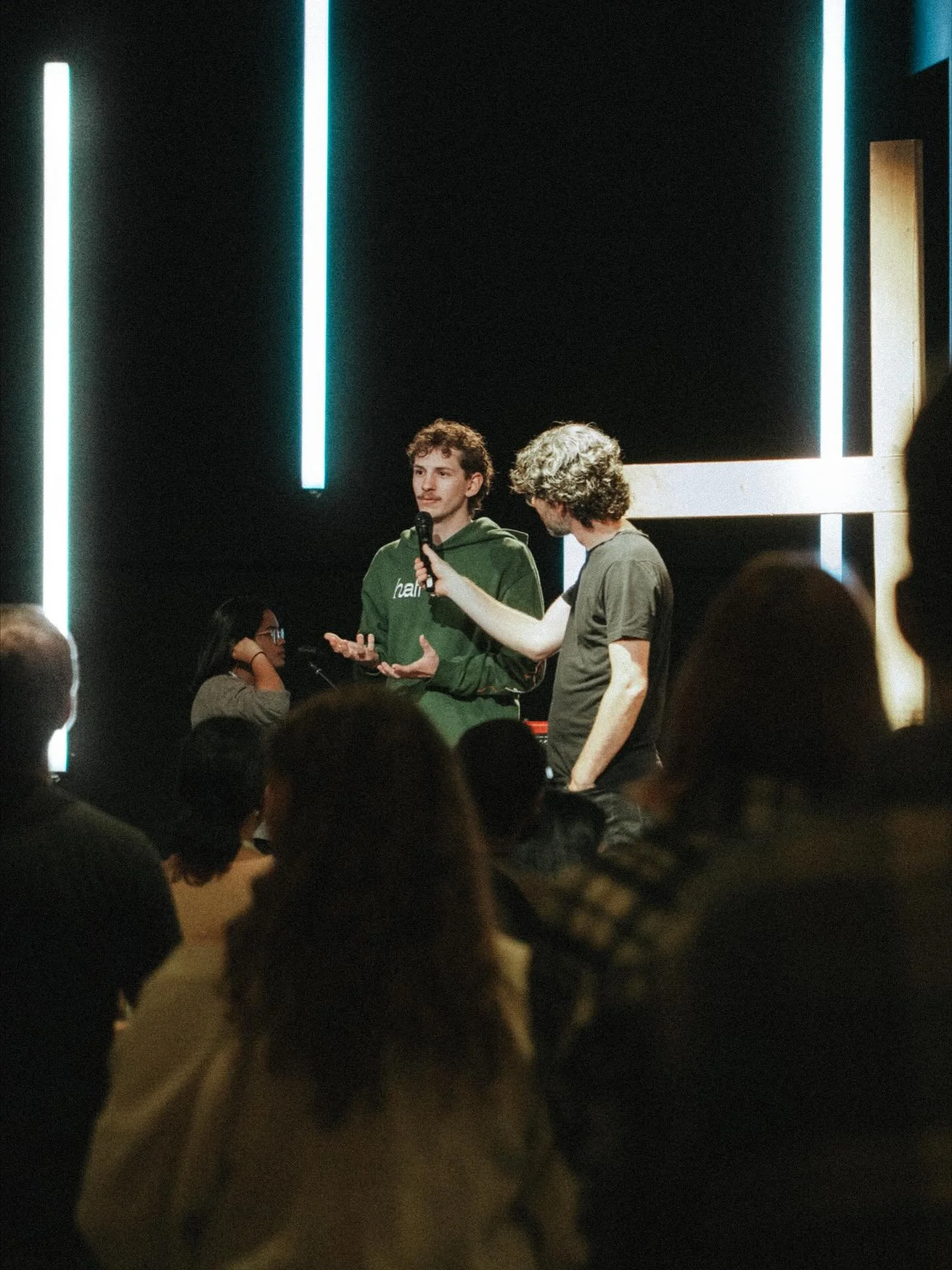 A young man shares a testimony of healing from stage during a worship night.