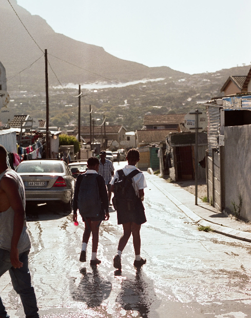 Jugendliche von iKhaya le Themba laufen durch das Township in die Schule.