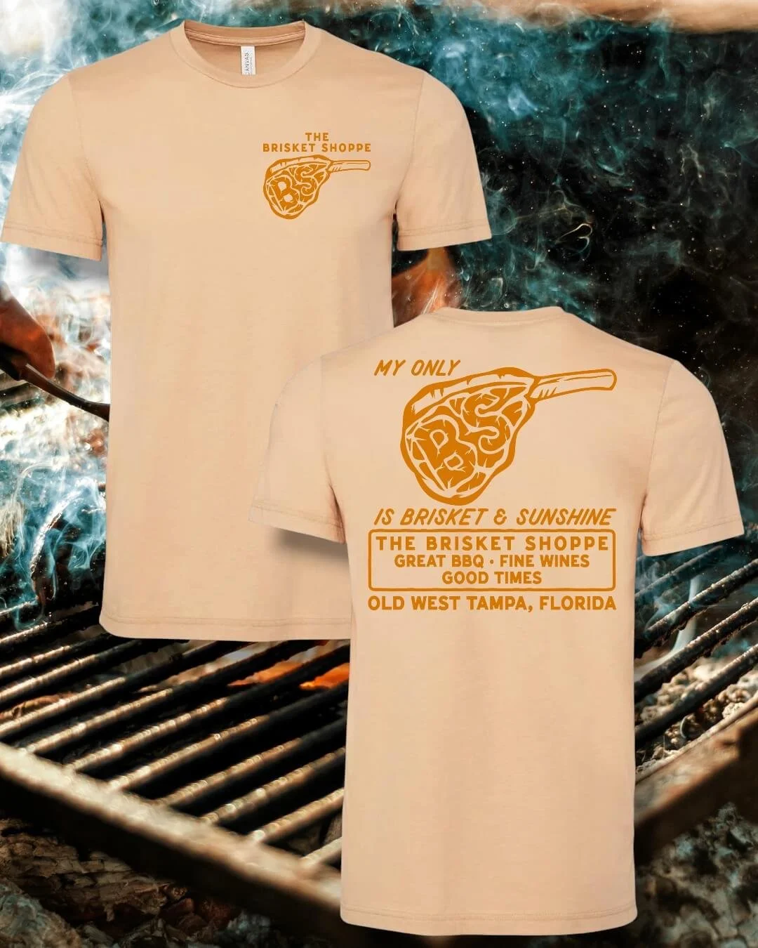 Cream-colored T-shirt with orange graphic and text, featuring a pizza slice with the words "The Brisket Shoppe" on the front and back. The back text reads "My only is brisket & sunshine. The Brisket Shoppe. Great BBQ. Fine Wines. Good Times. Old West Tampa, Florida." The shirts are displayed against a background of a BBQ grill with flames and smoke.