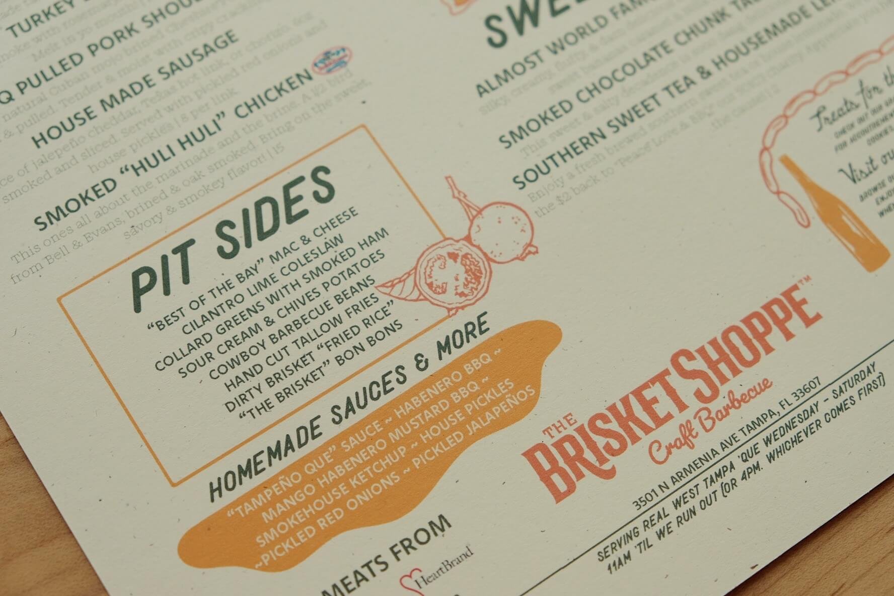 Close-up of a menu featuring smoked house-made sausage, pit sides, and homemade sauces and more at a barbecue restaurant.