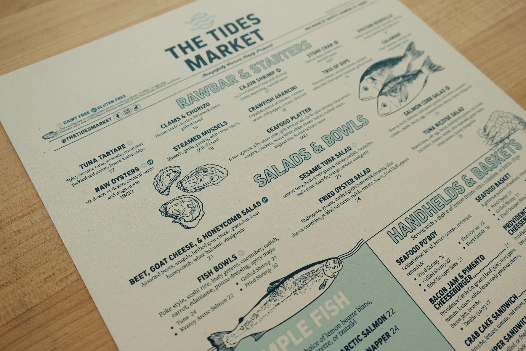 Restaurant menu page titled 'The Tides Market' with sections for salads and bowls, seafood dishes, and illustrations of fish.