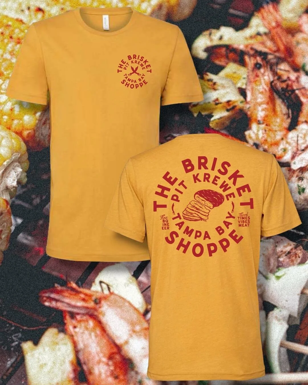 Two yellow T-shirts with red text and a graphic of a baked potato, set against a background of cooked food including shrimp and vegetables. The front of the shirts reads "The Brisket Pit Krew Tampa Bay Shoppe" with a small graphic of a cooking fork, and the back reads "The Brisket Shoppe Tampa Bay" with an image of a sliced baked potato and the words "Fire, BBQ, Clean, Good Times, Vibes, Meat."