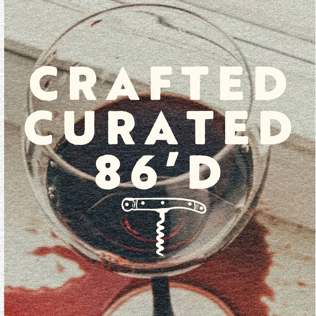A glass of red wine on a wooden surface with spilled wine underneath. Overlaid text reads 'Crafted Curated 86'D' with a corkscrew illustration.