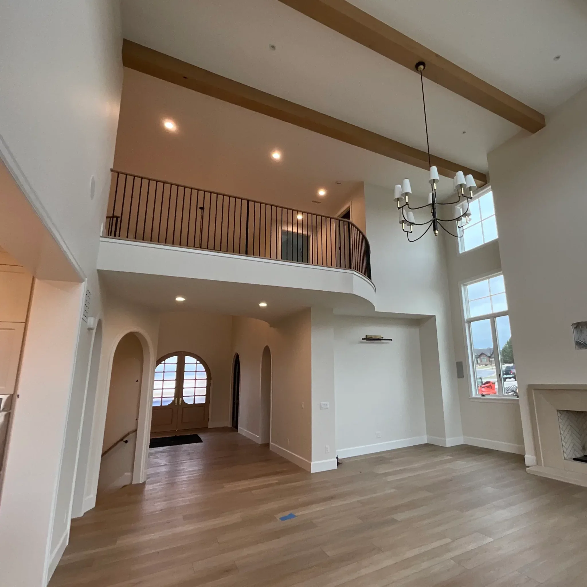 Interior residential painting project showing a newly finished custom home interior with high ceilings, clean white walls, exposed beams, and detailed trim work.