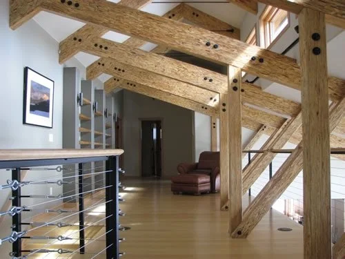 Modern mountain home interior featuring exposed timber framing, custom wood beams, neutral painted walls, open-concept design, and professionally finished interior surfaces in Colorado residence.