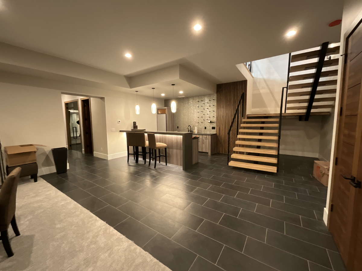 Modern basement and lower-level interior painting project featuring floating wood staircases, black metal railings, custom wet bar finishes, accent wall detailing, and contemporary architectural design. Professional interior painting and fine finish 