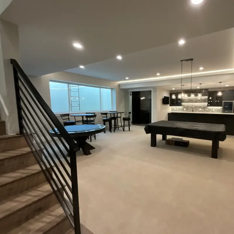 Custom home painting in a finished lower-level residential interior with clean wall surfaces, recessed lighting, black railing detail, and coordinated finish work.