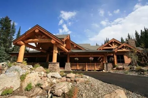 Luxury mountain home exterior with professionally painted wood siding, exposed timber beams, stone accents, and detailed exterior finishes in Colorado mountain setting.