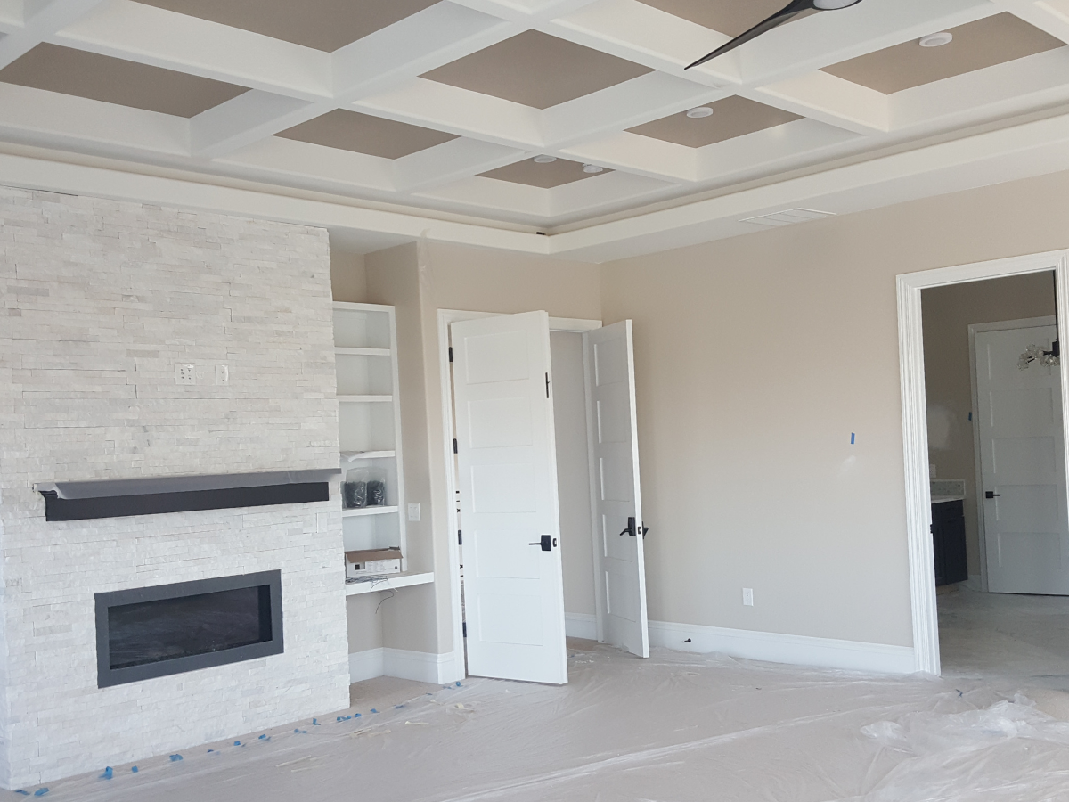 Luxury bedroom interior with custom coffered ceiling painting, neutral wall colors, modern fireplace, and detailed finish work in high-end Colorado home.