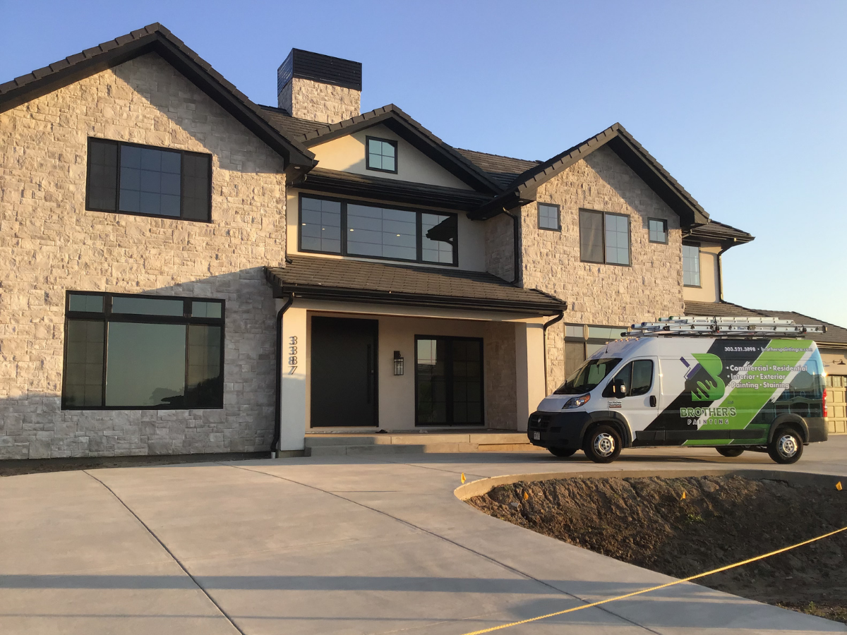 Luxury custom home exterior painting project featuring modern stonework, black trim accents, and high-end architectural finishes. Professional residential exterior painting and staining services for new construction homes and upscale custom propertie